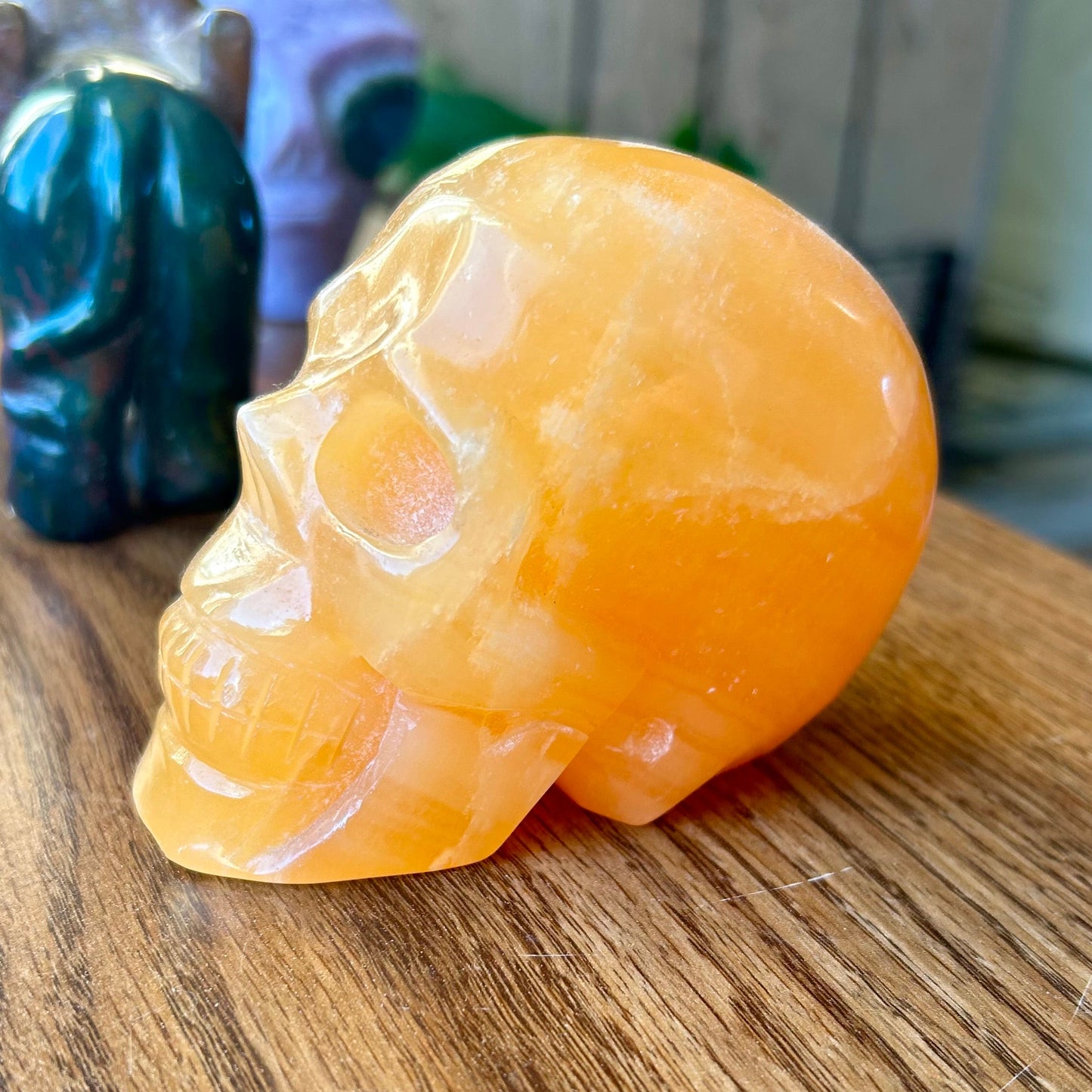 Orange stone skull sculpture on a wooden surface with blurred background