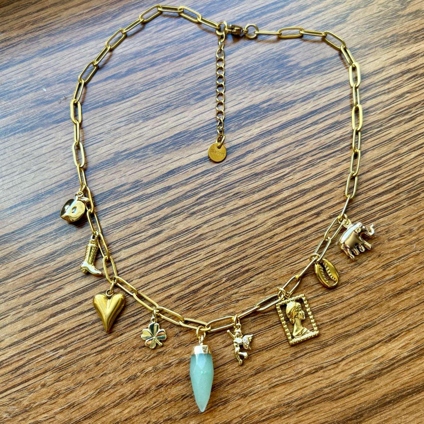 Gold necklace with various charms on a wooden surface