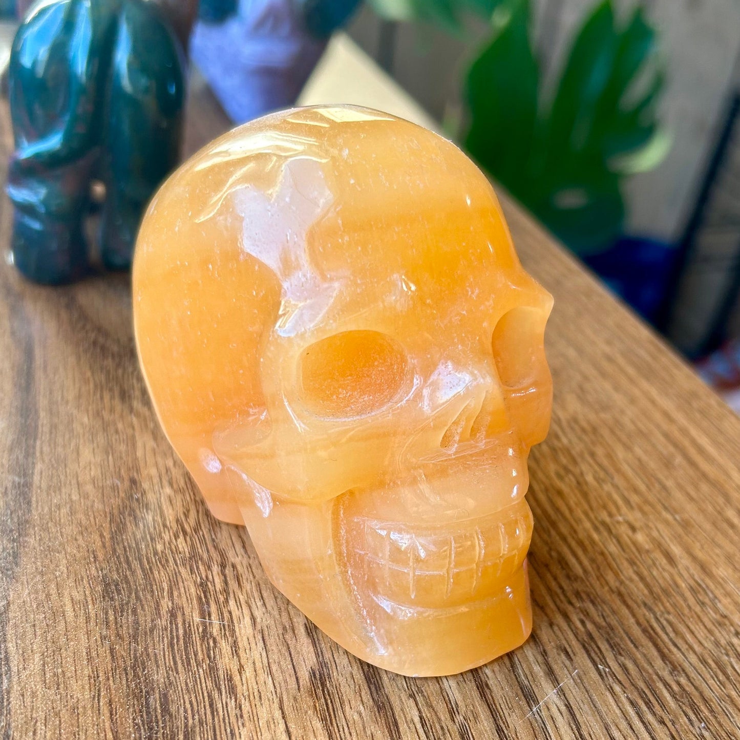 Carved stone skull on a wooden surface with decorative items in the background