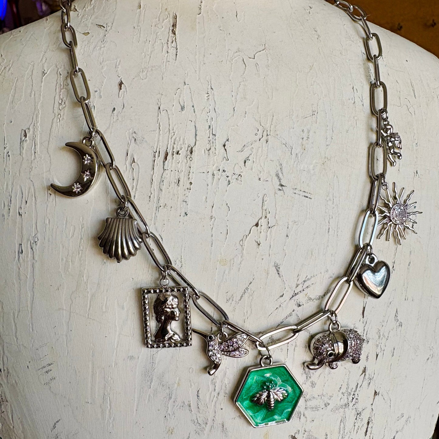 Necklace with various charms on a mannequin bust.
