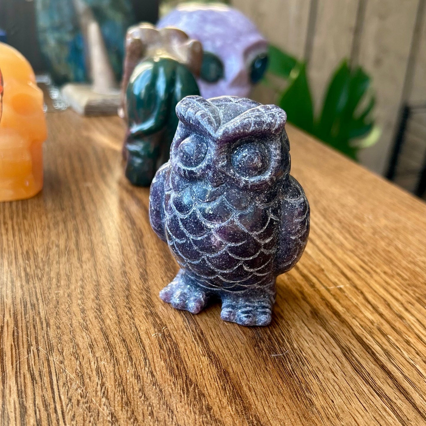 Decorative owl figurine on a wooden surface with blurred background