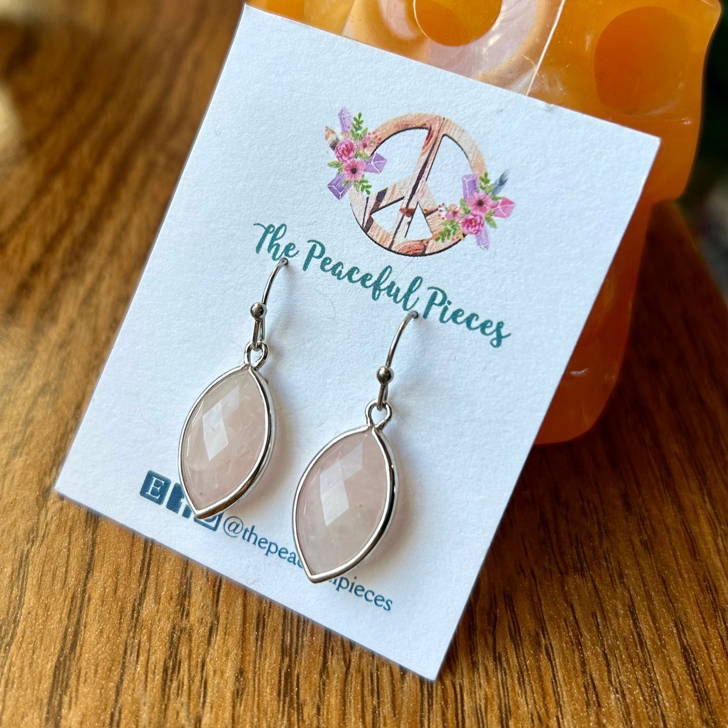 Earrings on a 'The Peaceful Pieces' branded card with a decorative 'D' logo.