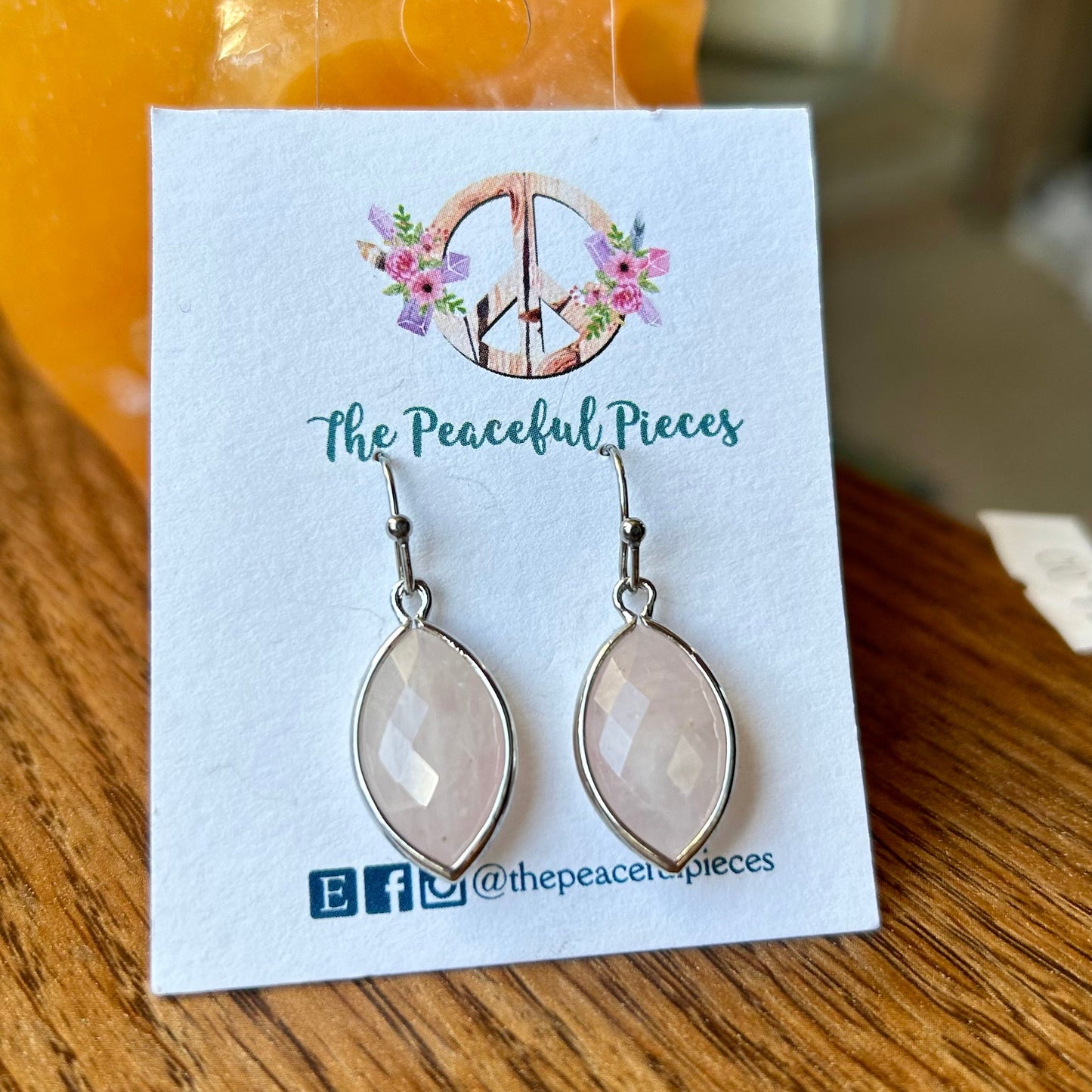Earrings on a 'The Peaceful Pieces' branded card with a blurred background