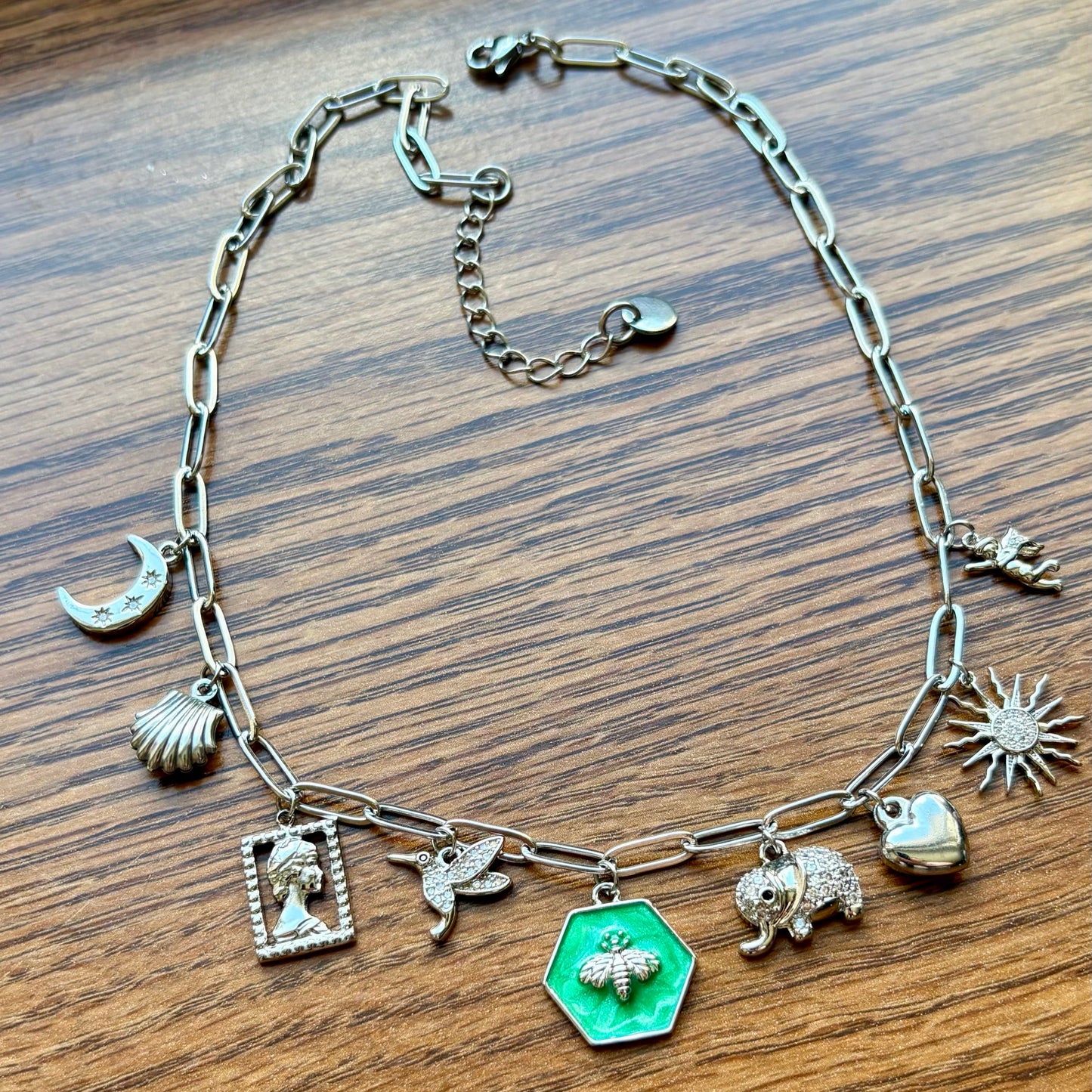 Silver necklace with various charms on a wooden surface