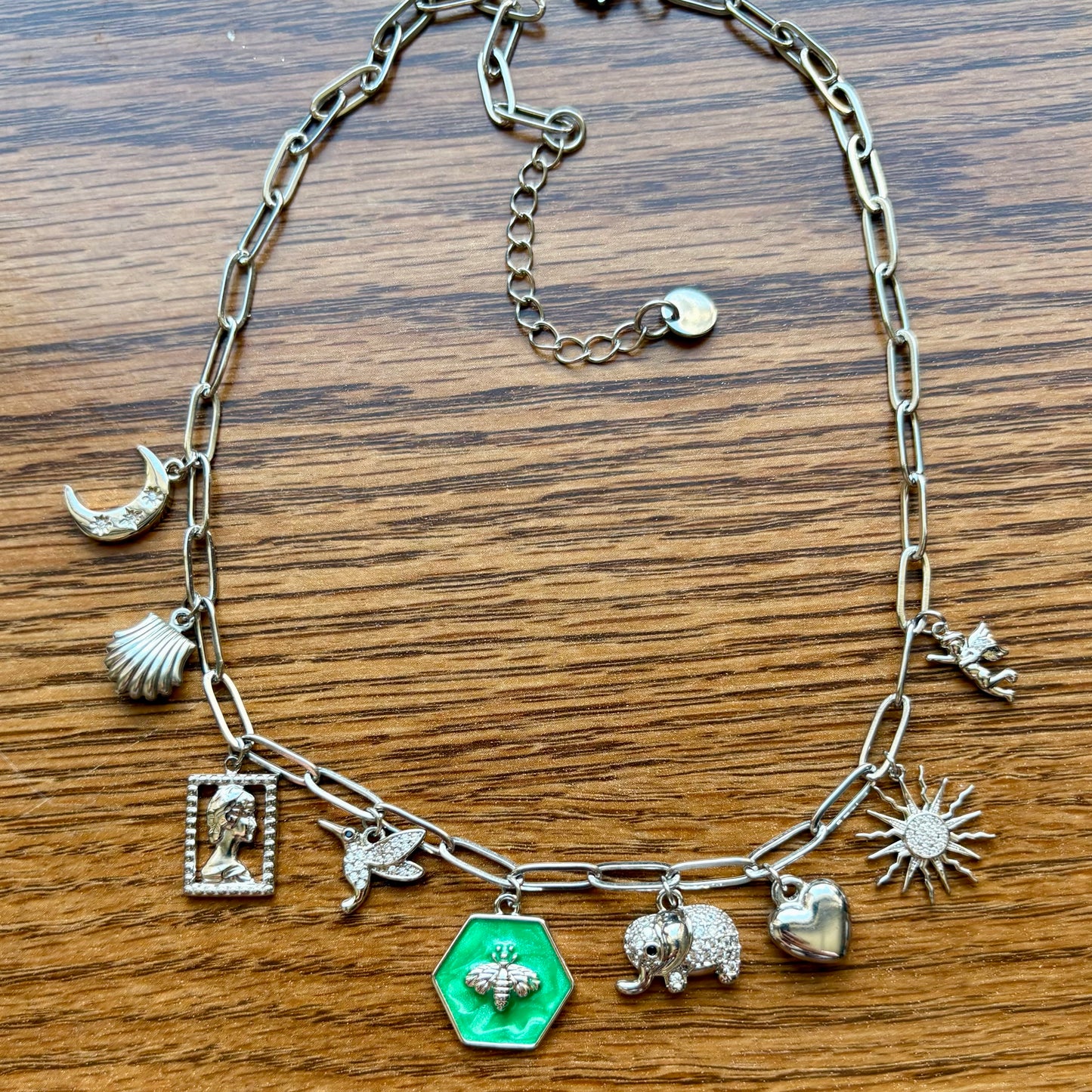 Silver chain bracelet with various charms on a wooden surface