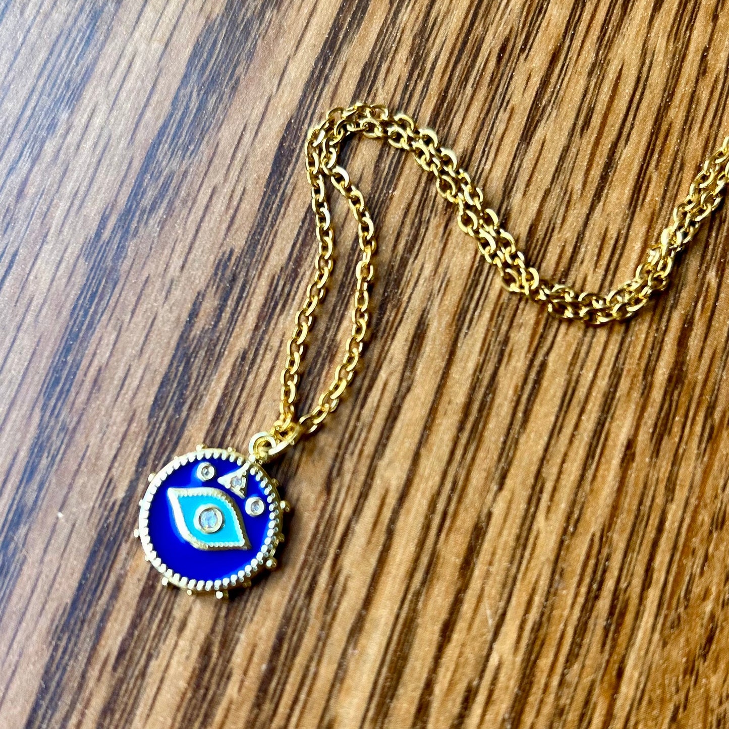 Gold necklace with a blue pendant on a wooden surface
