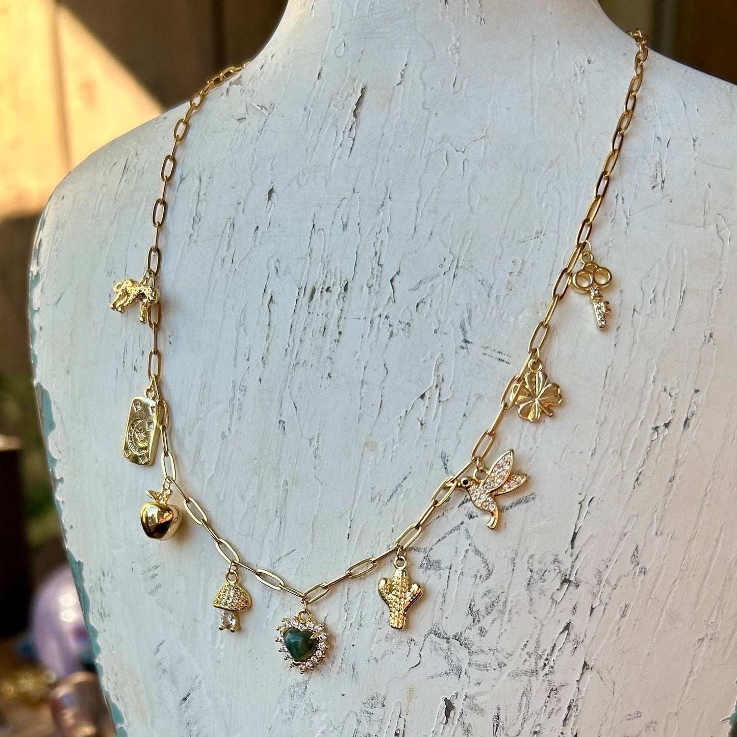 Gold necklace with green gemstone on a white mannequin bust.