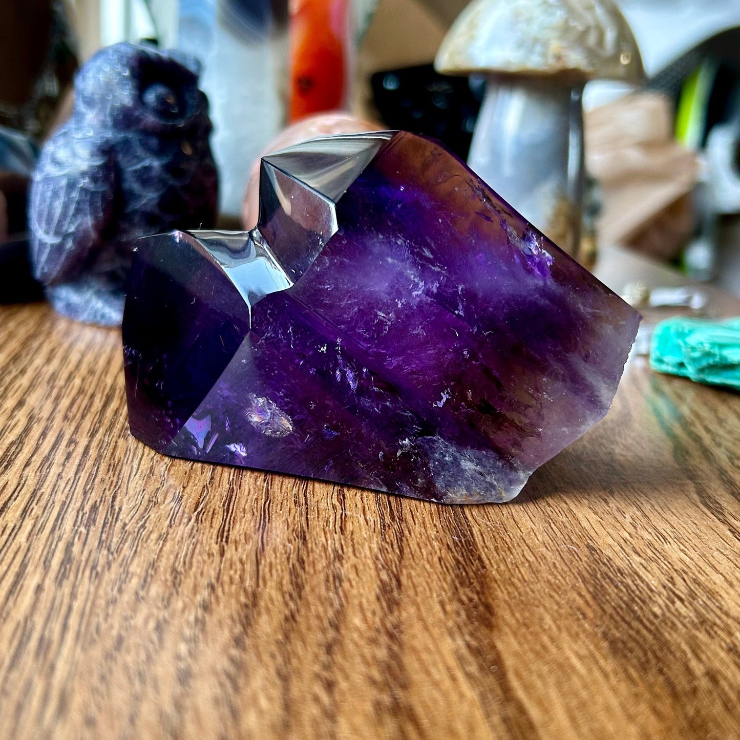 Amethyst crystal on a wooden surface with other crystals in the background