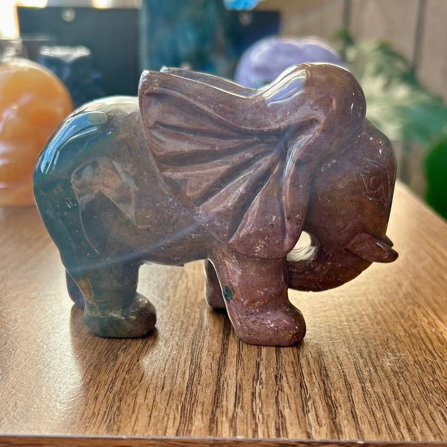 Carved stone elephant figurine on a wooden surface with blurred background