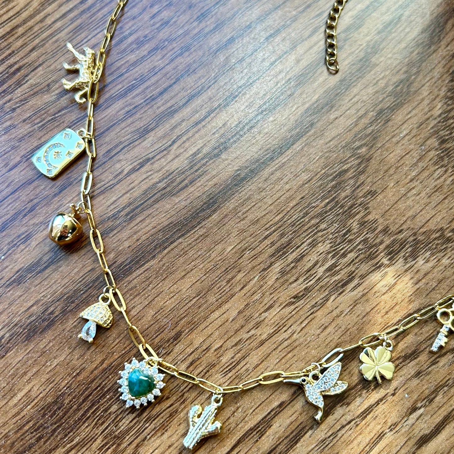 Gold necklace with various charms on a wooden surface