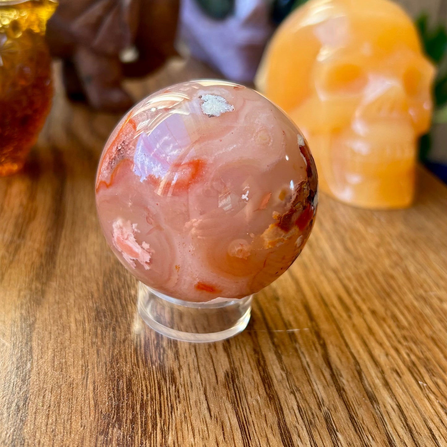 Decorative agate sphere on a clear stand with other decorative items in the background.