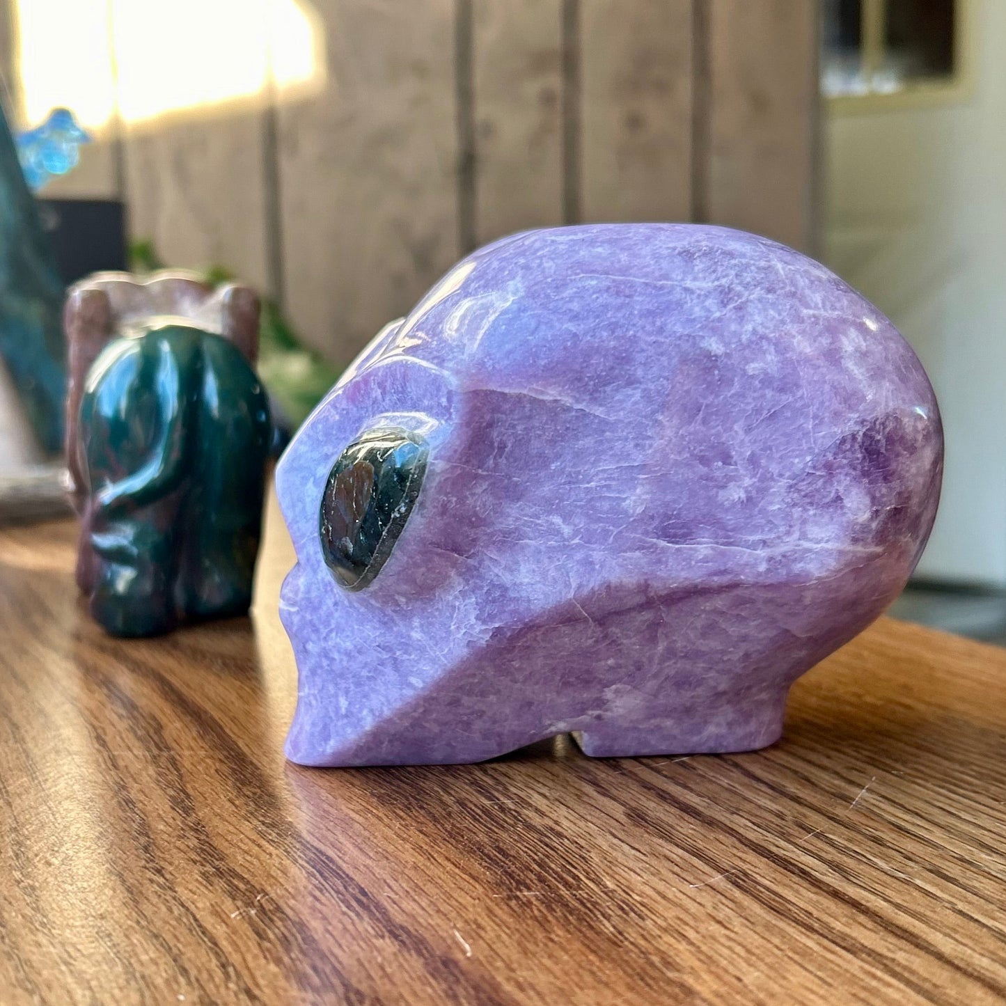 Purple crystal rabbit figurine on a wooden surface with a blurred background