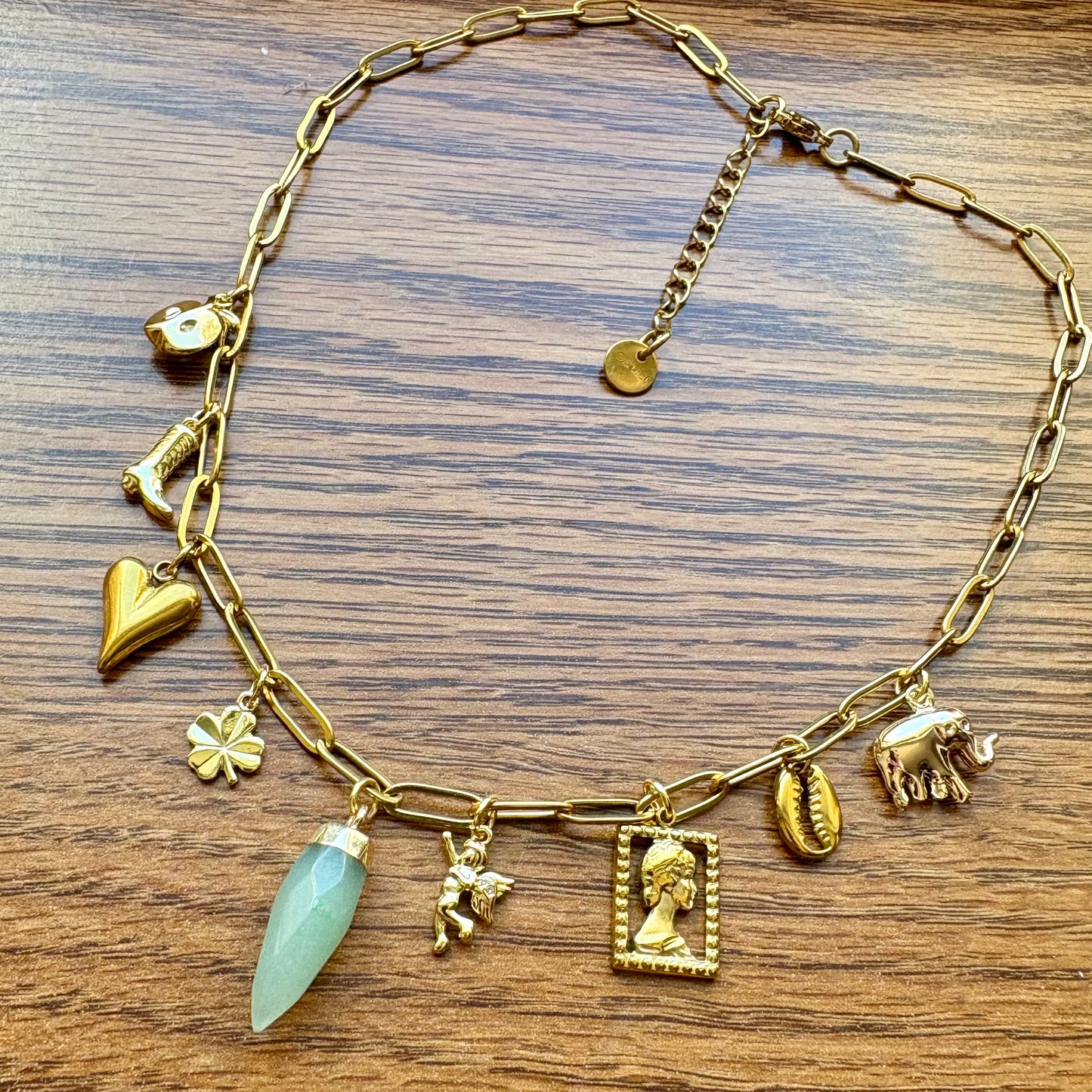 Gold charm bracelet with various charms on a wooden surface