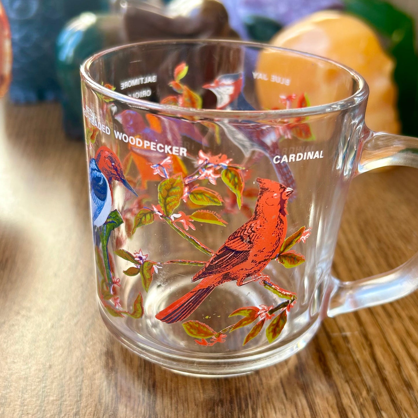 Clear glass mug with bird illustrations on a wooden surface