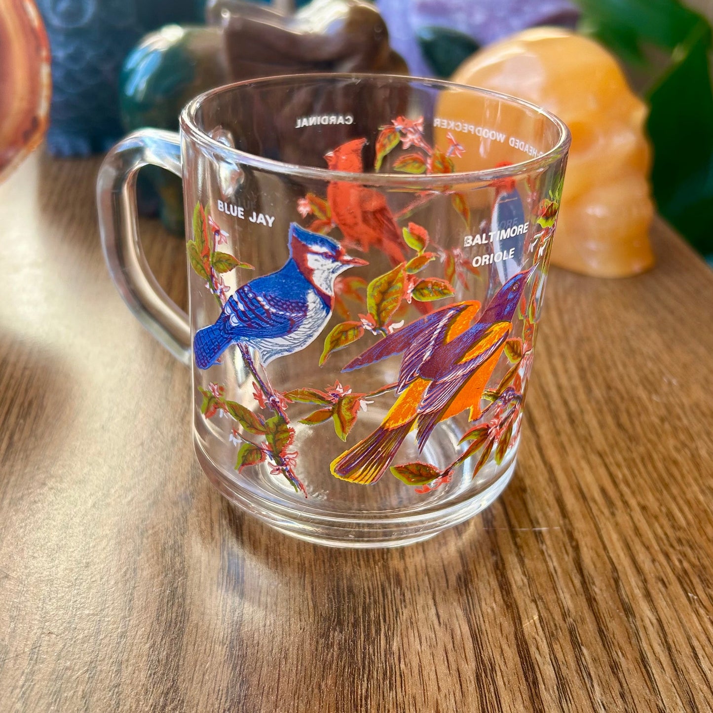 Glass mug with colorful fish design on a wooden surface