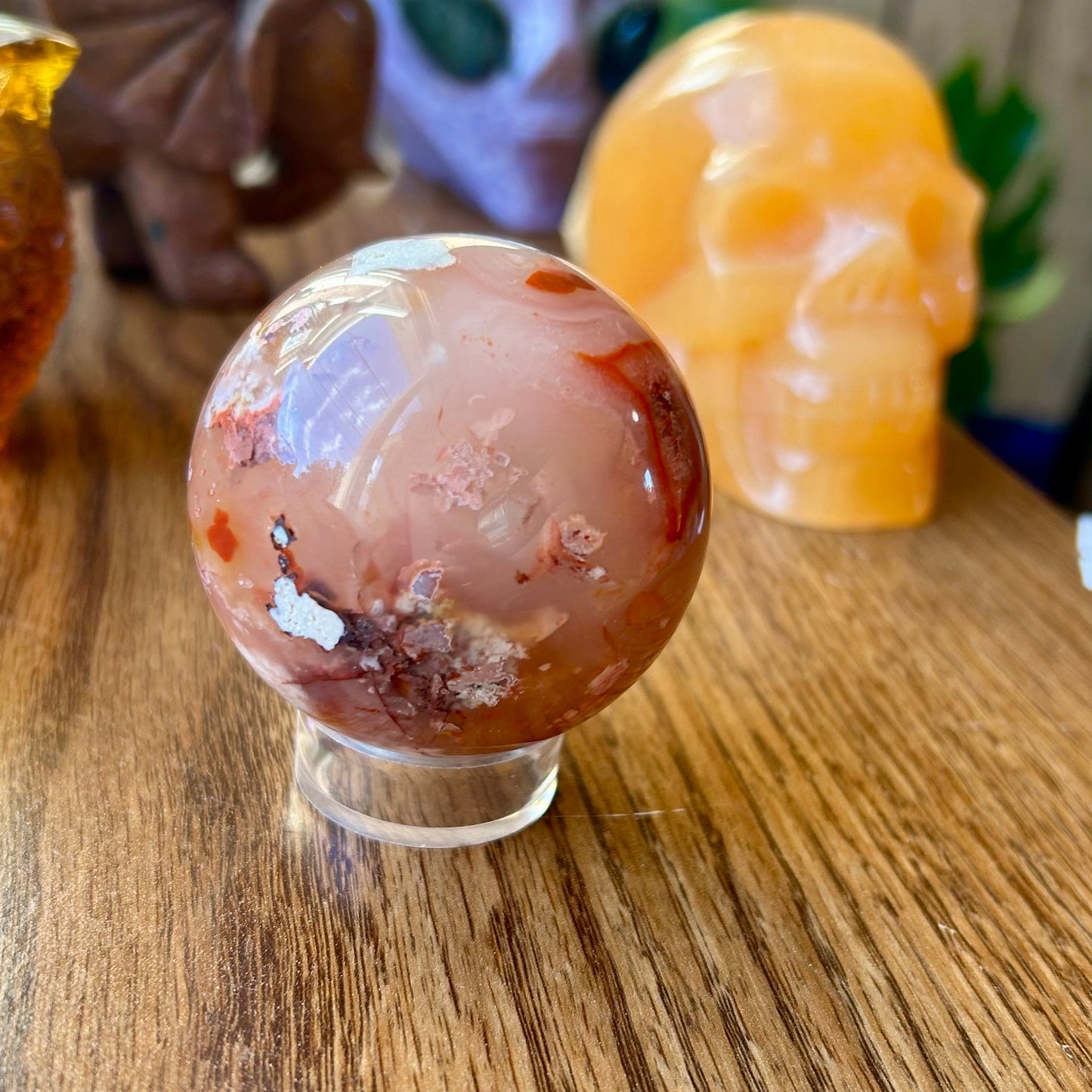 Decorative crystal ball on a wooden surface with other decorative items in the background.