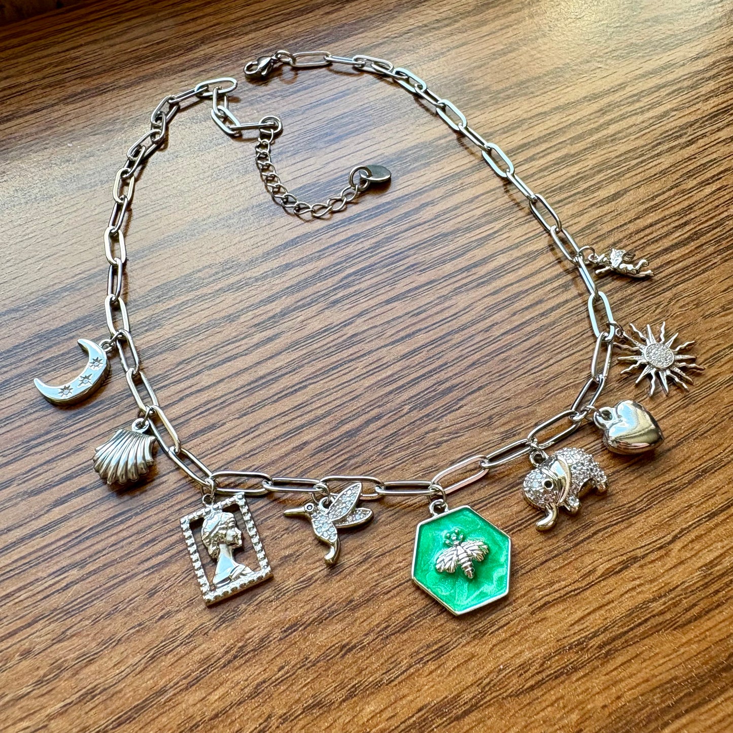 Silver charm bracelet with various charms on a wooden surface