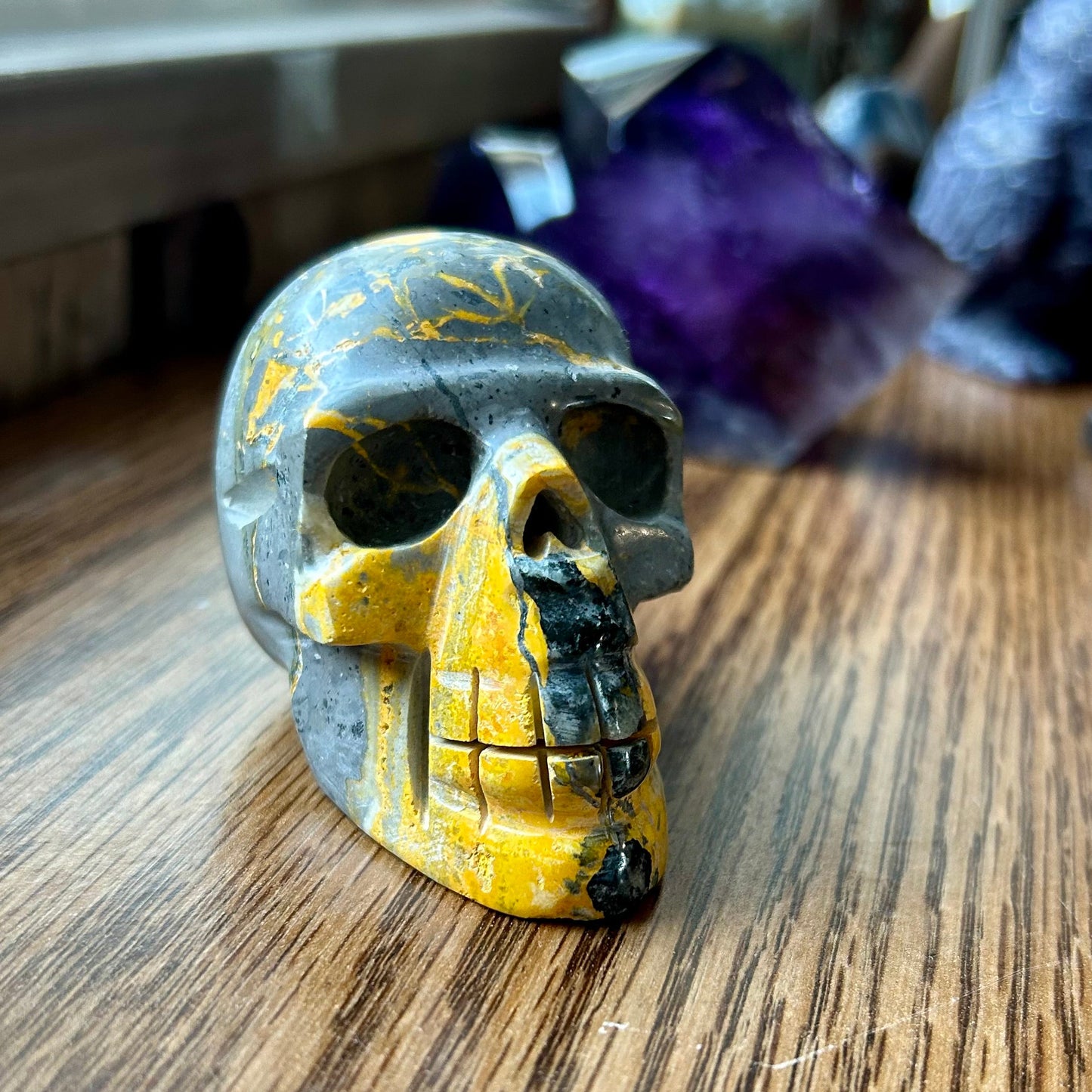 Small marbled skull figurine on a wooden surface with blurred background