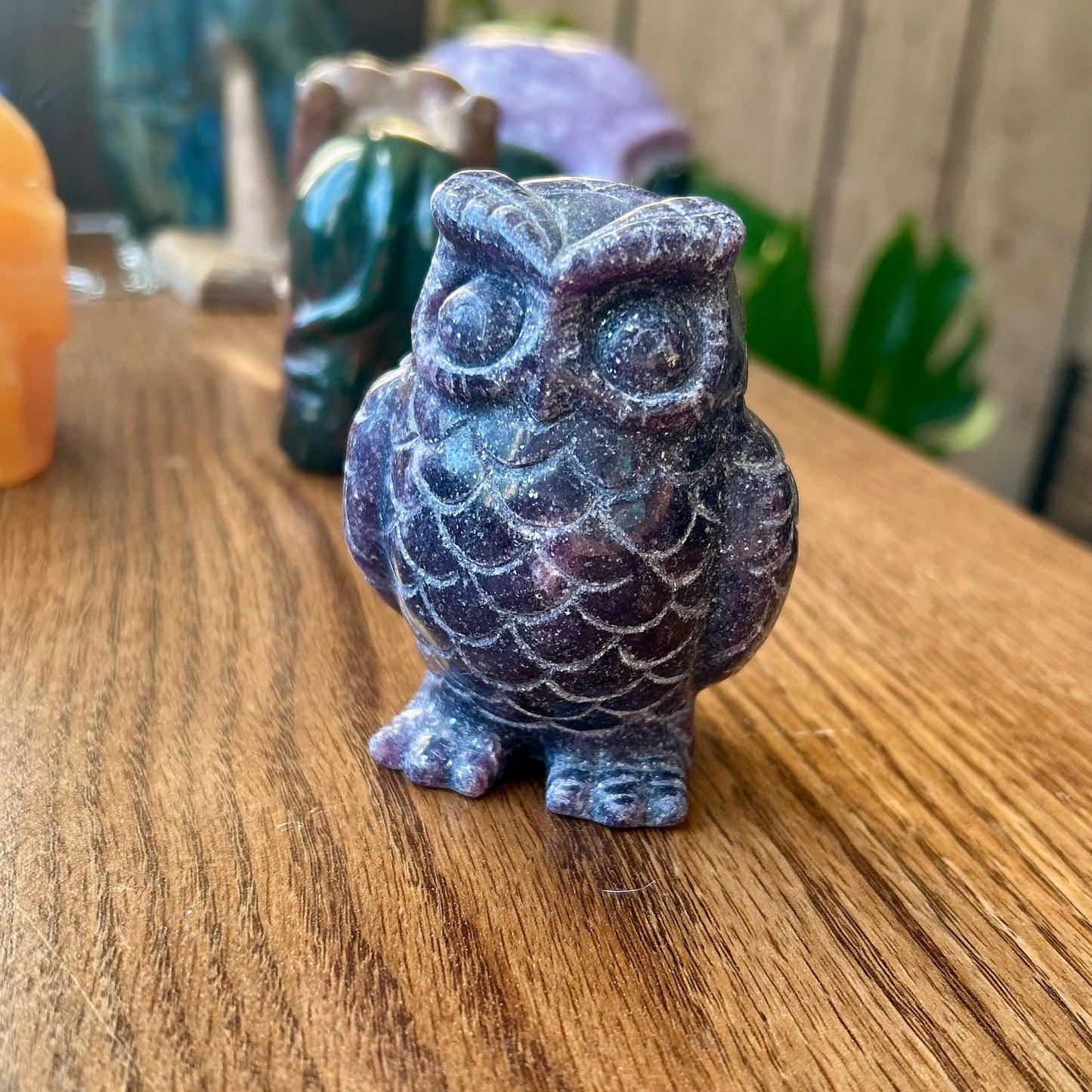 Blue owl figurine on a wooden surface with a blurred background
