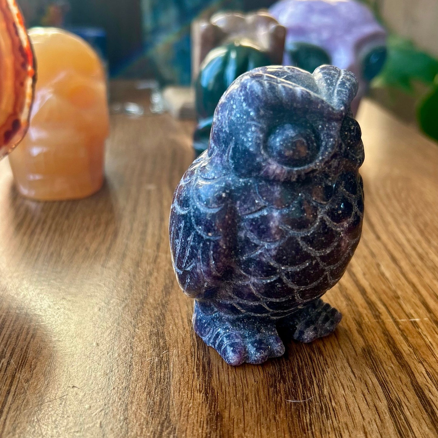 Blue stone owl figurine on a wooden surface with blurred background