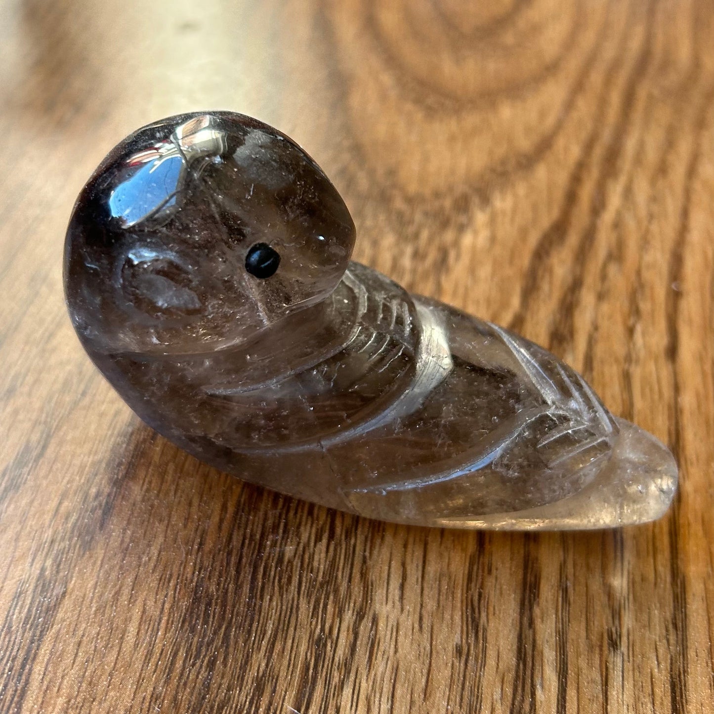 Smoky crystal bird figurine on a wooden surface
