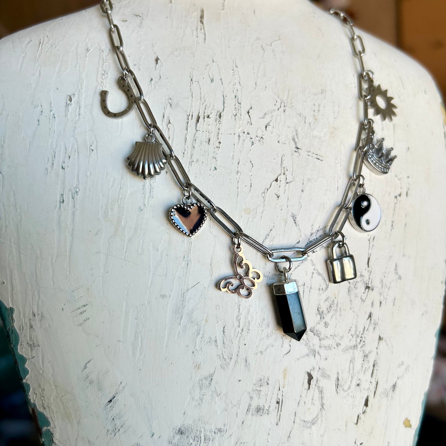 Necklace with various charms on a mannequin head against a white background