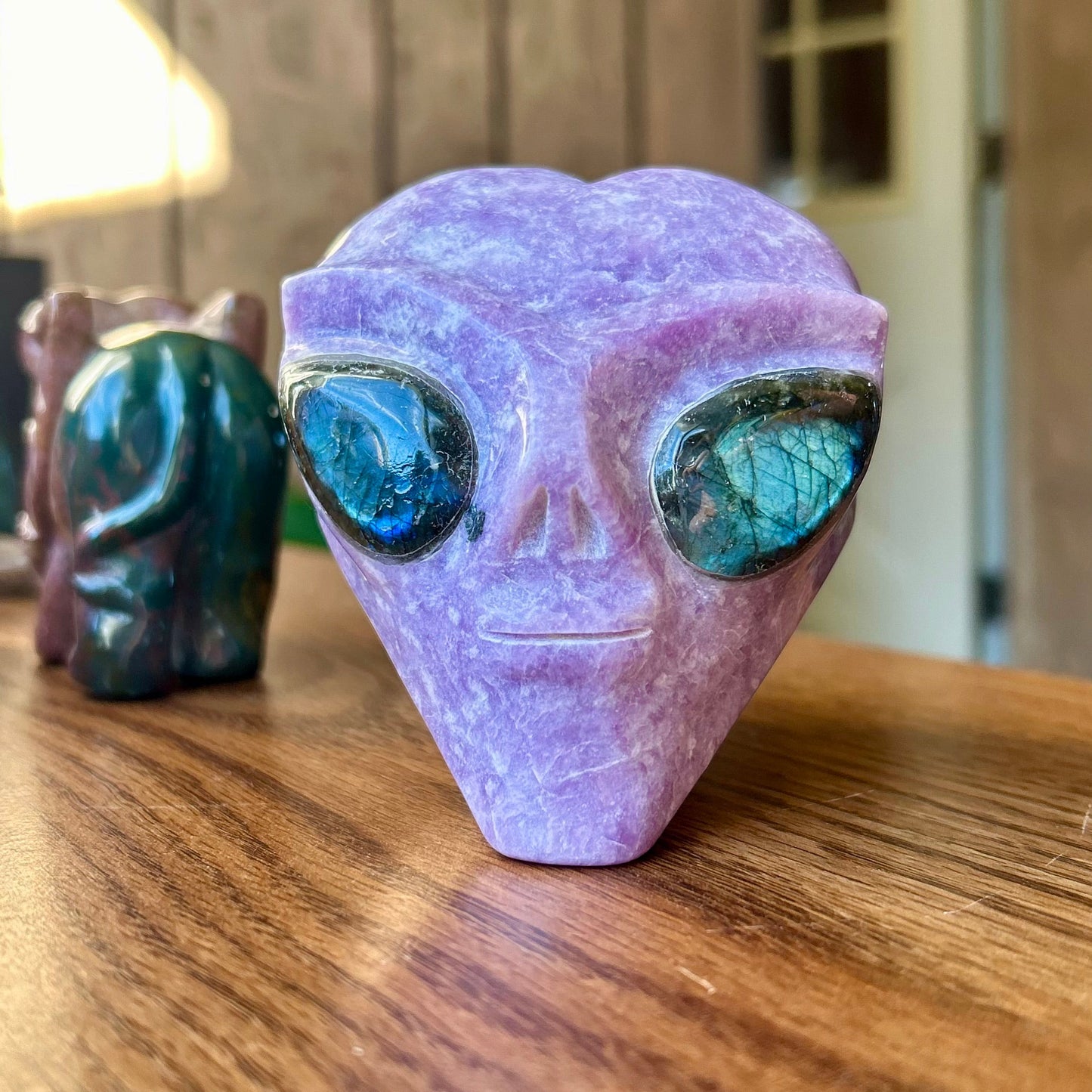 Purple alien head figurine on a wooden surface with blurred background