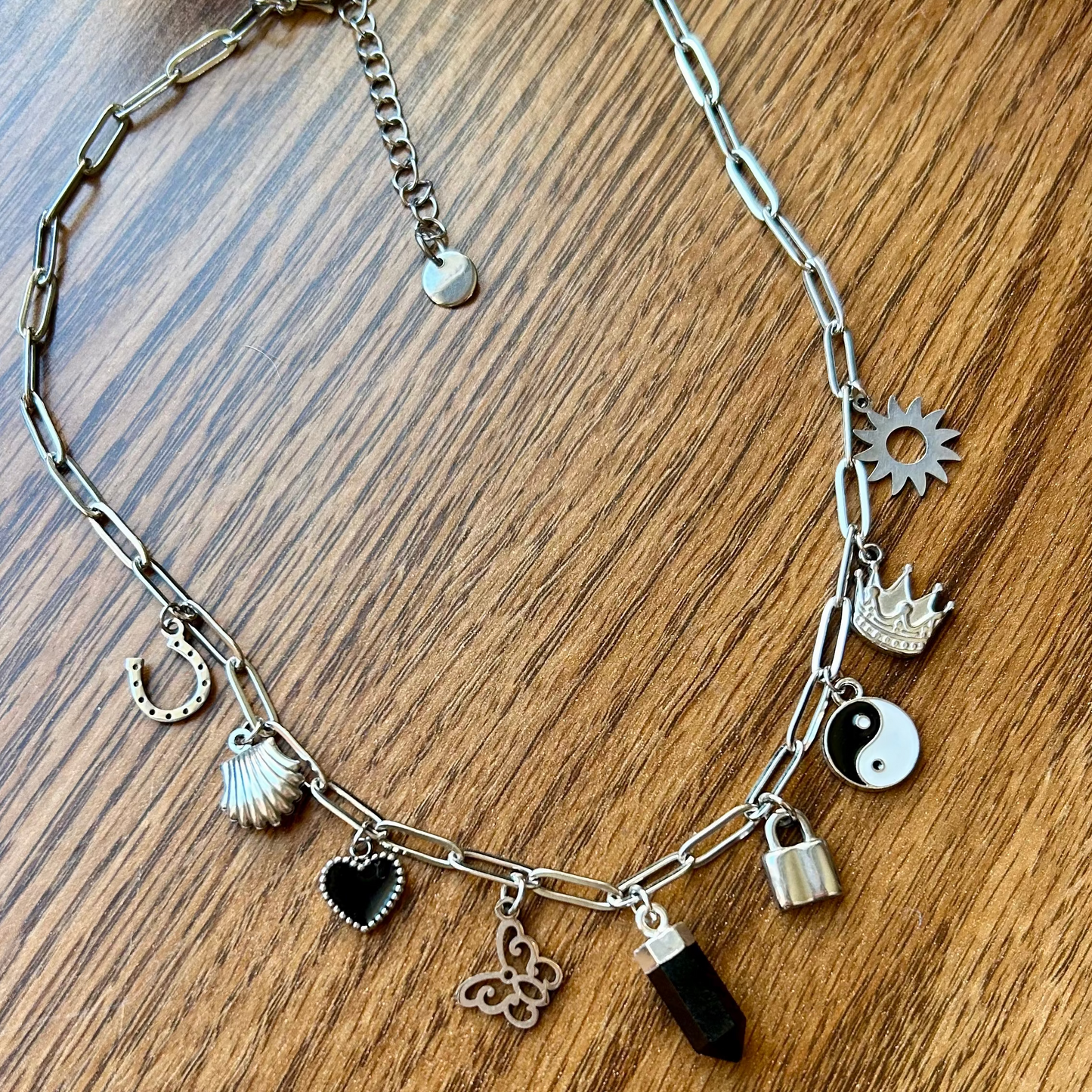 Silver necklace with various charms on a wooden surface