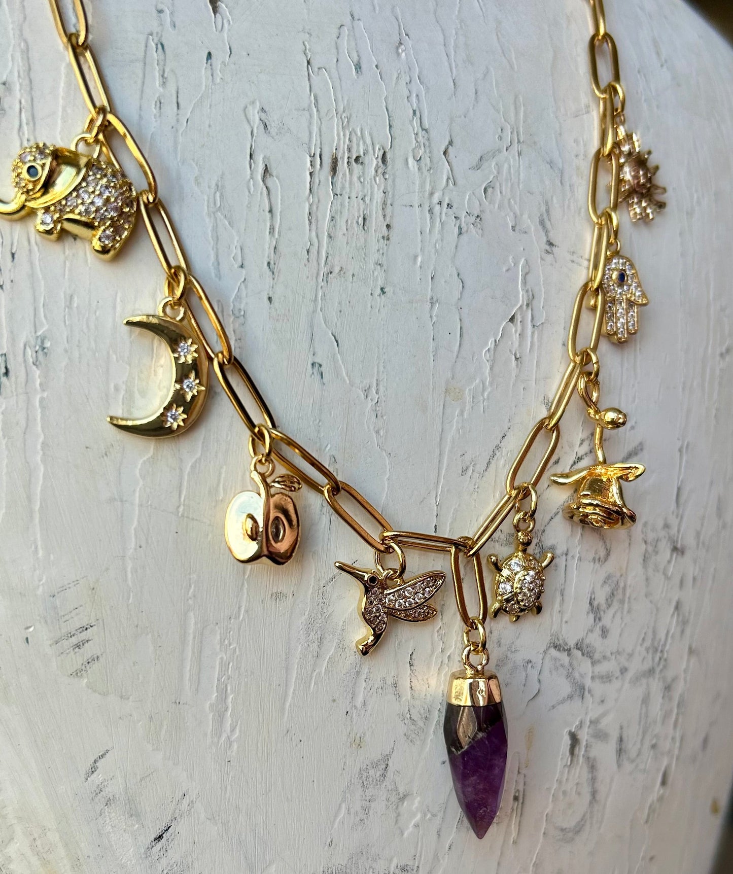 Gold necklace with various charms on a white surface
