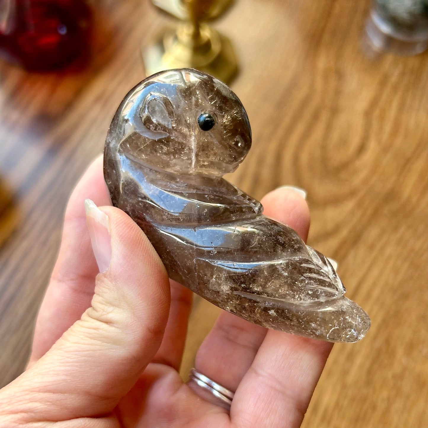 Hand holding a crystal feather pendant on a wooden surface
