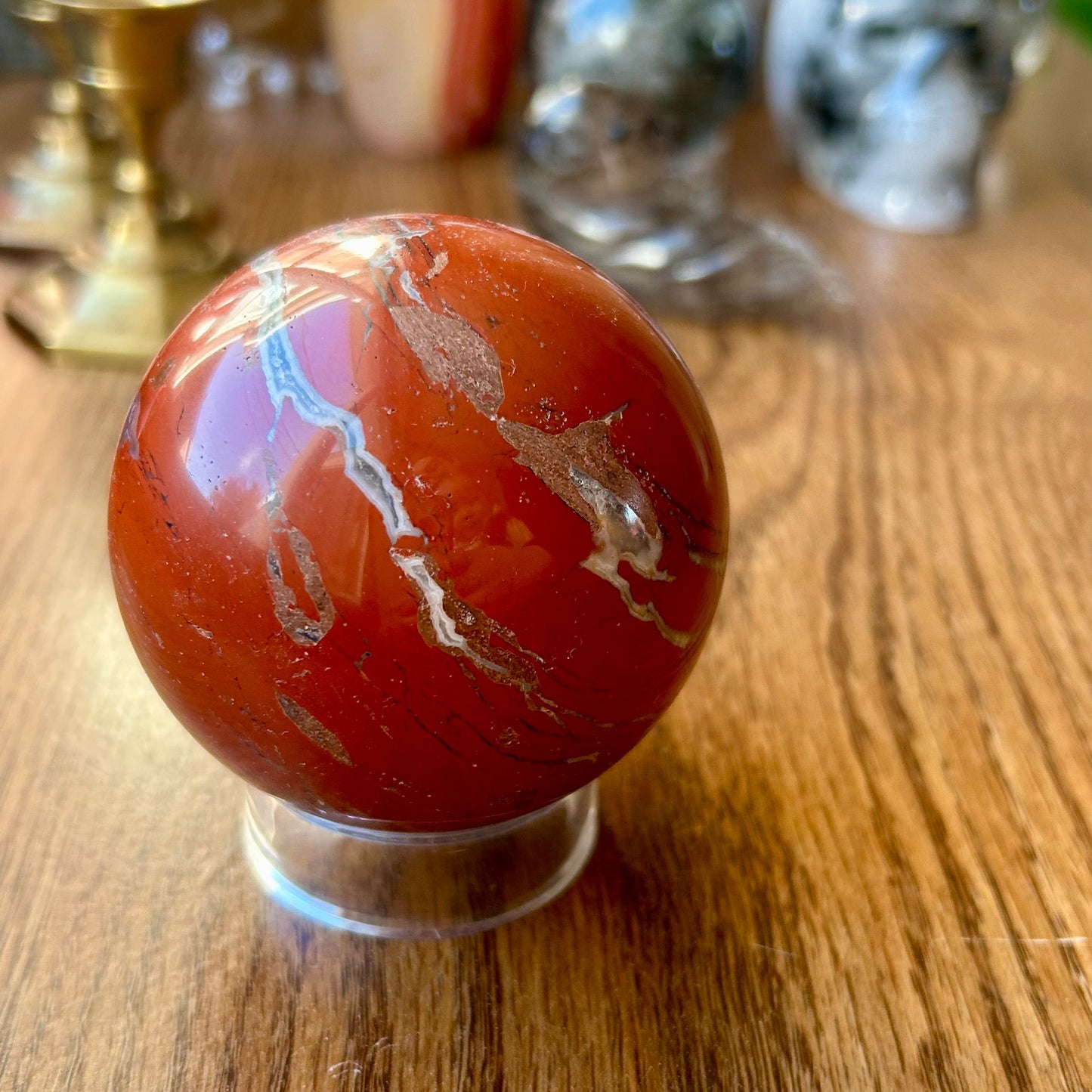 Marbled red and white sphere on a wooden surface with decorative items in the background