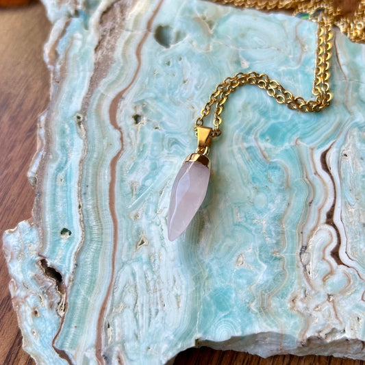 Necklace with a pink pendant on a textured stone surface