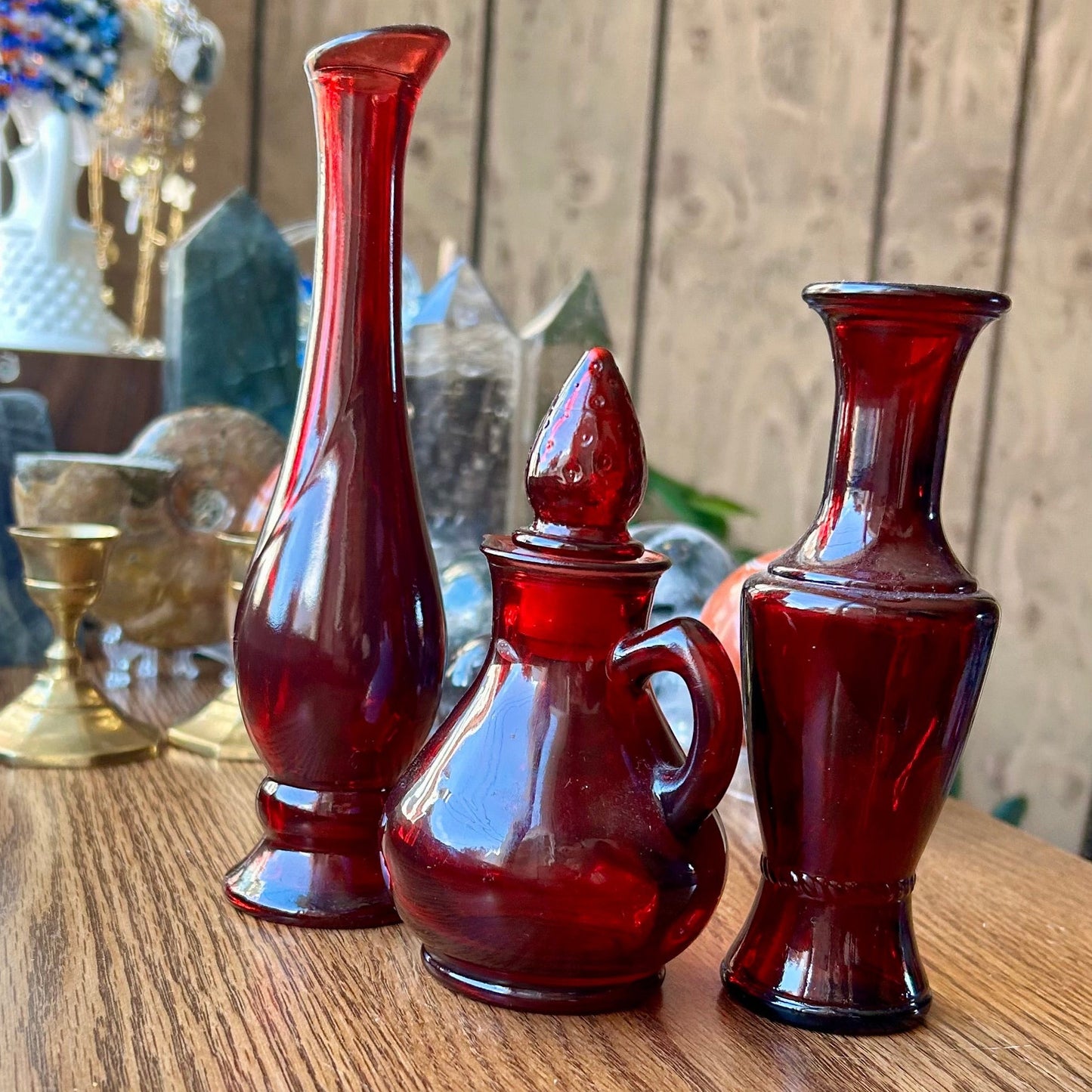 Three red glass bottles on a wooden surface with a blurred background