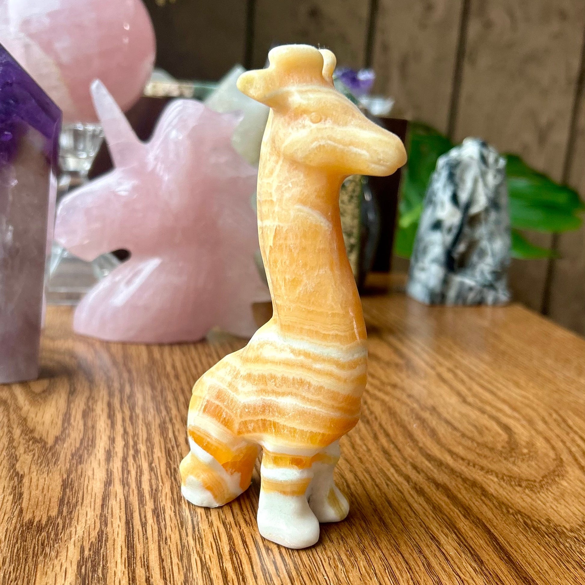 Decorative giraffe figurine on a wooden surface with other decorative items in the background.