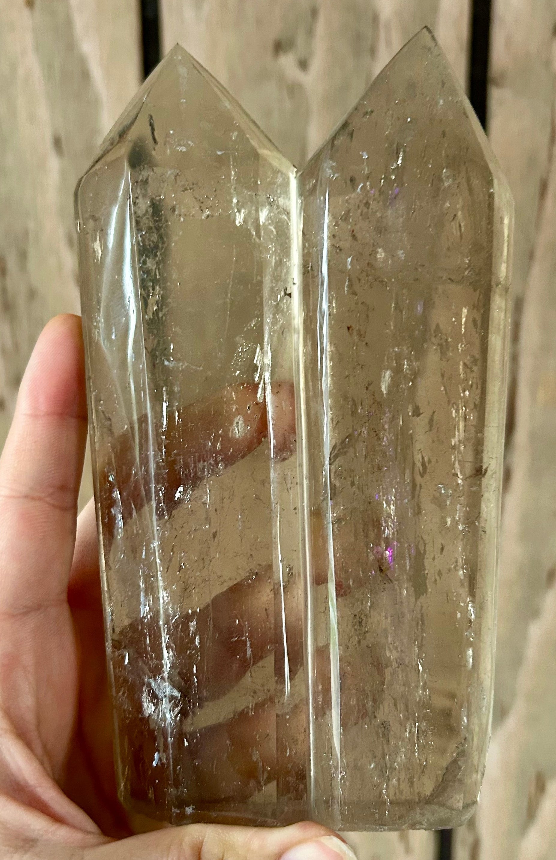 Clear crystal tower held by a hand against a wooden background