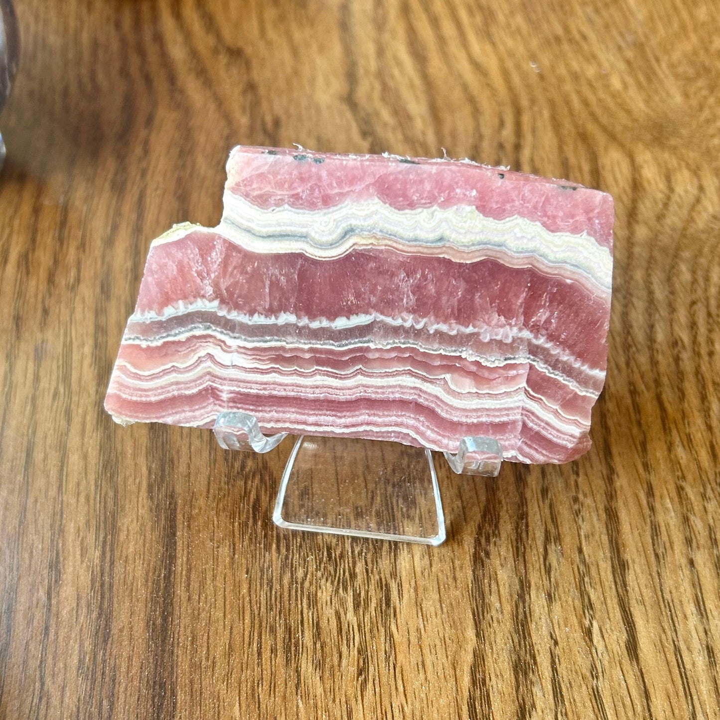 Stack of layered pink and white stone on a clear stand against a wooden background