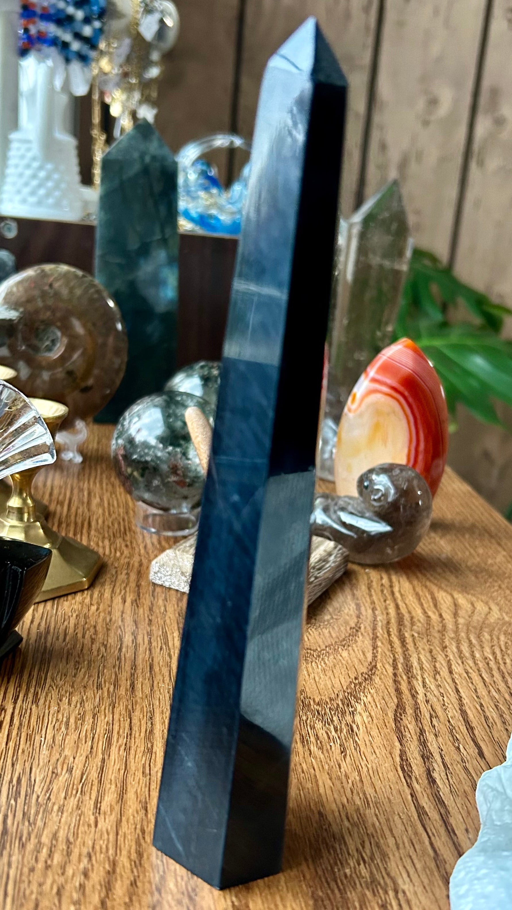 Blue crystal on a wooden surface with other crystals and objects in the background