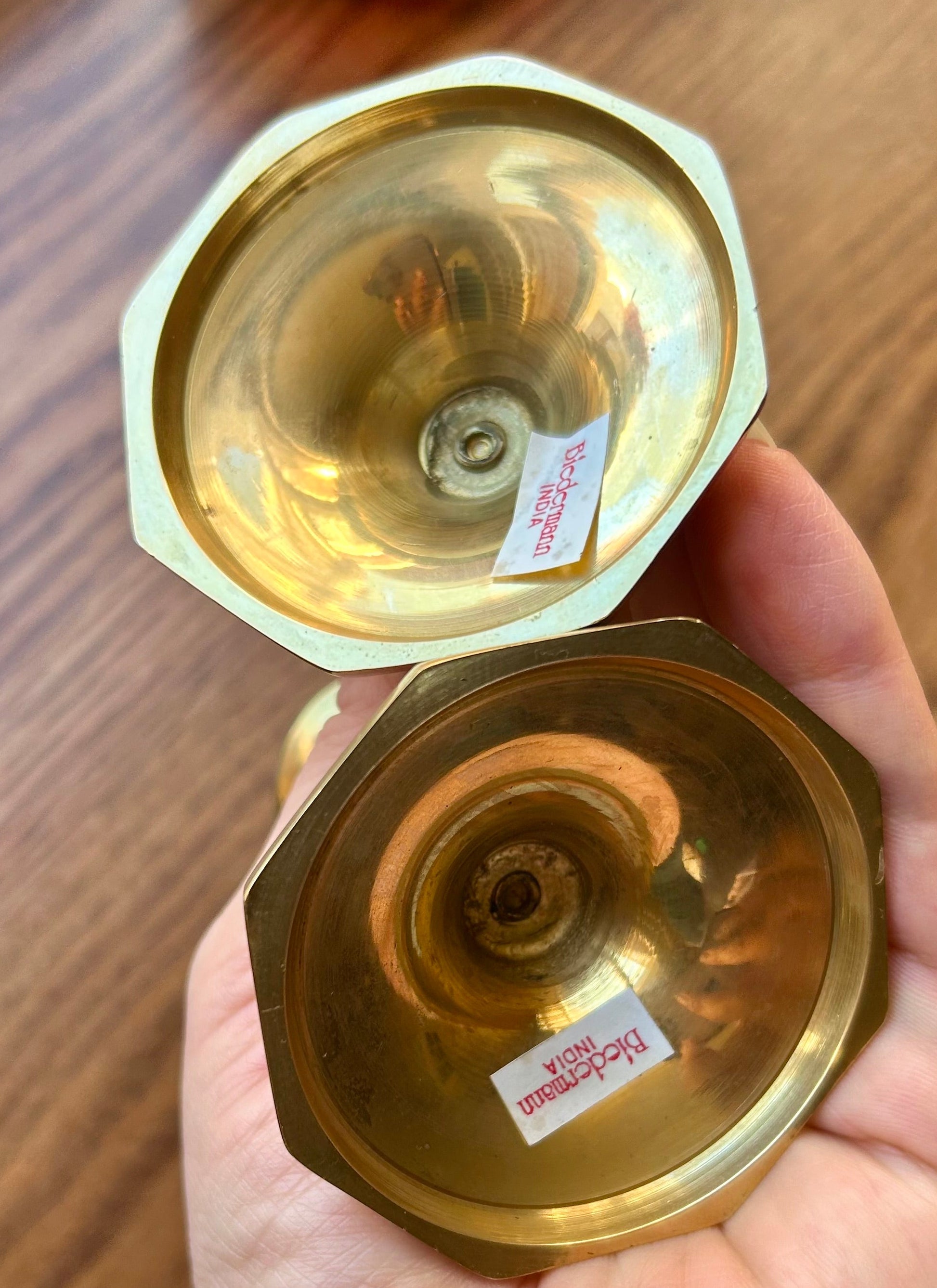 Hand holding a brass lamp with a wooden background