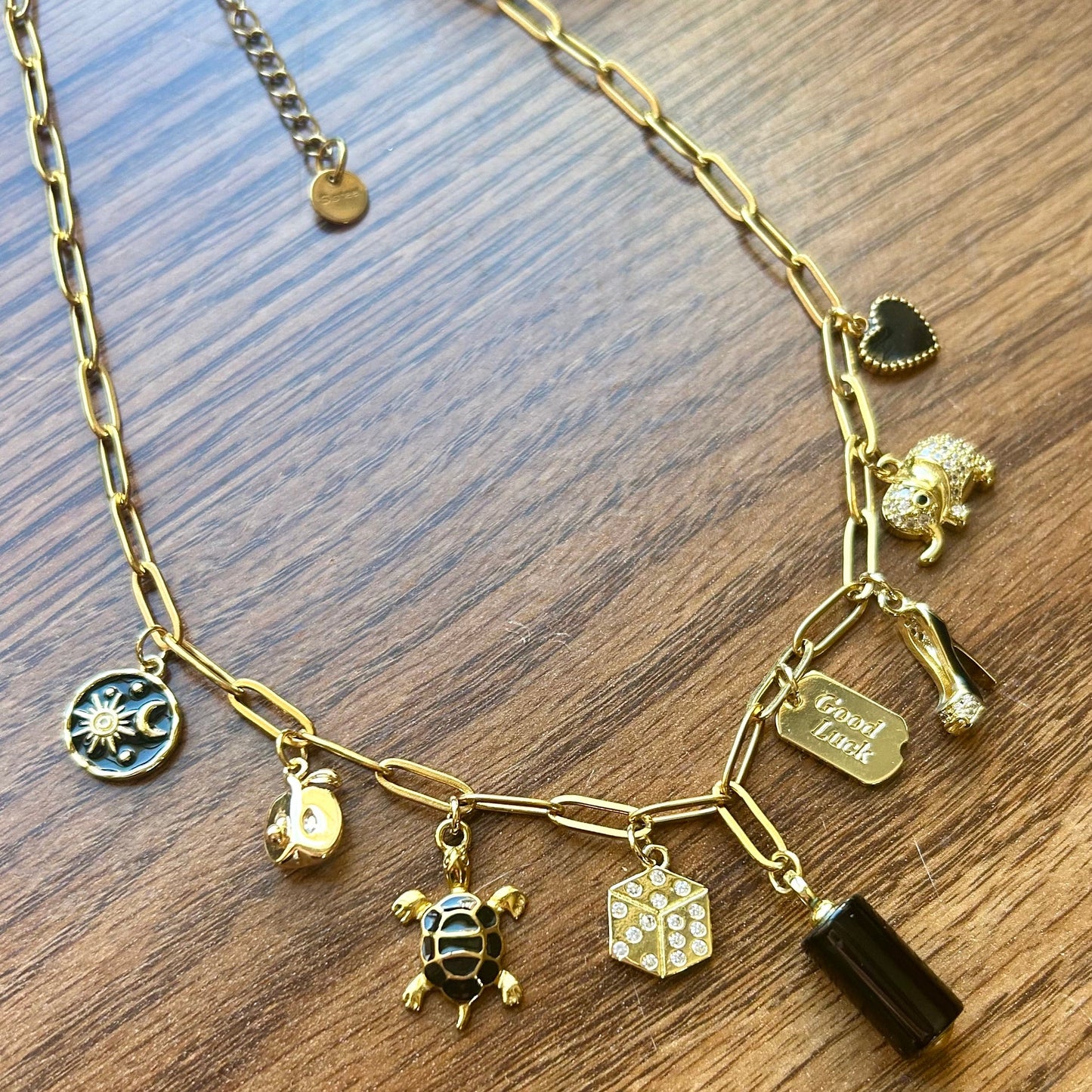 Gold necklace with various charms on a wooden surface