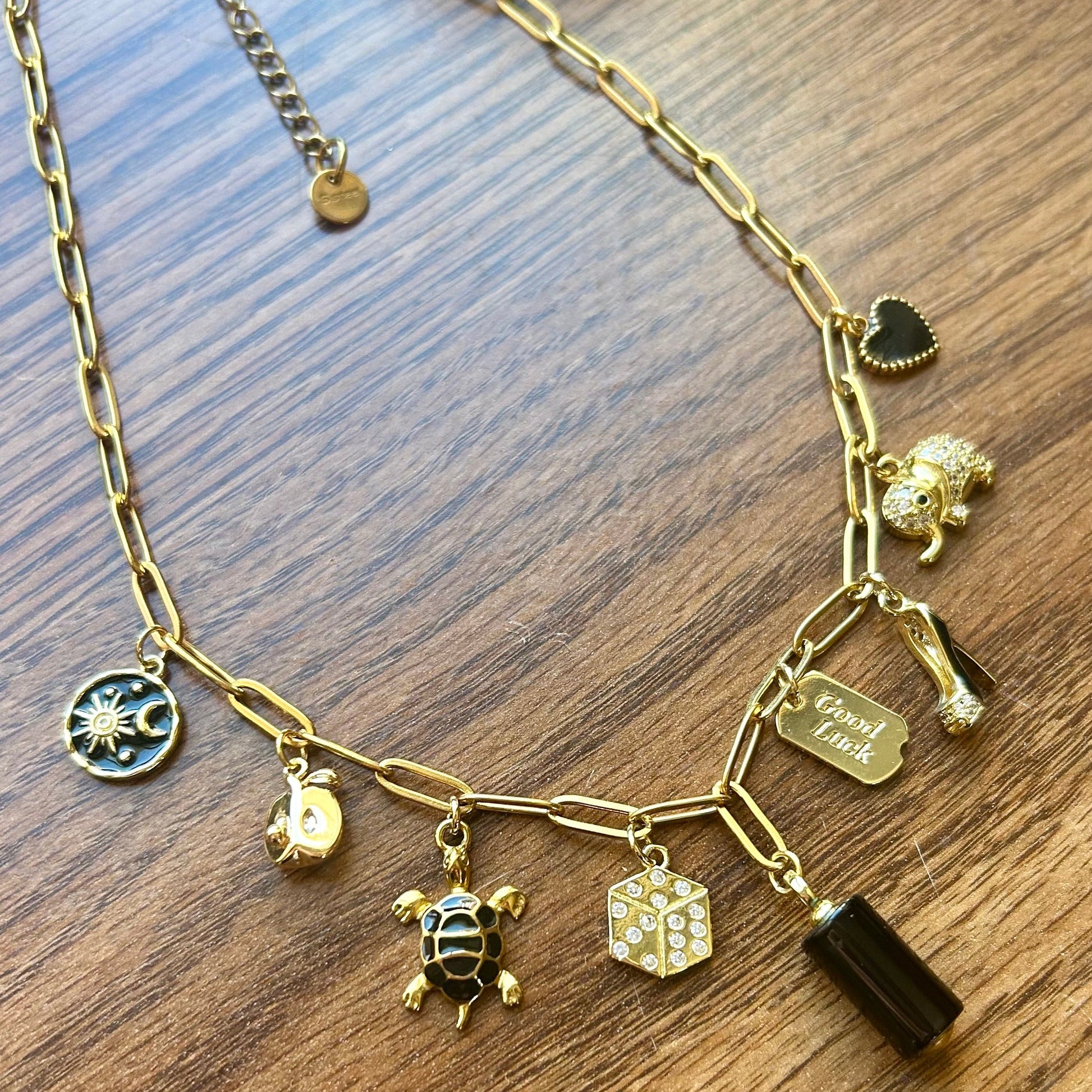 Gold necklace with various charms on a wooden surface