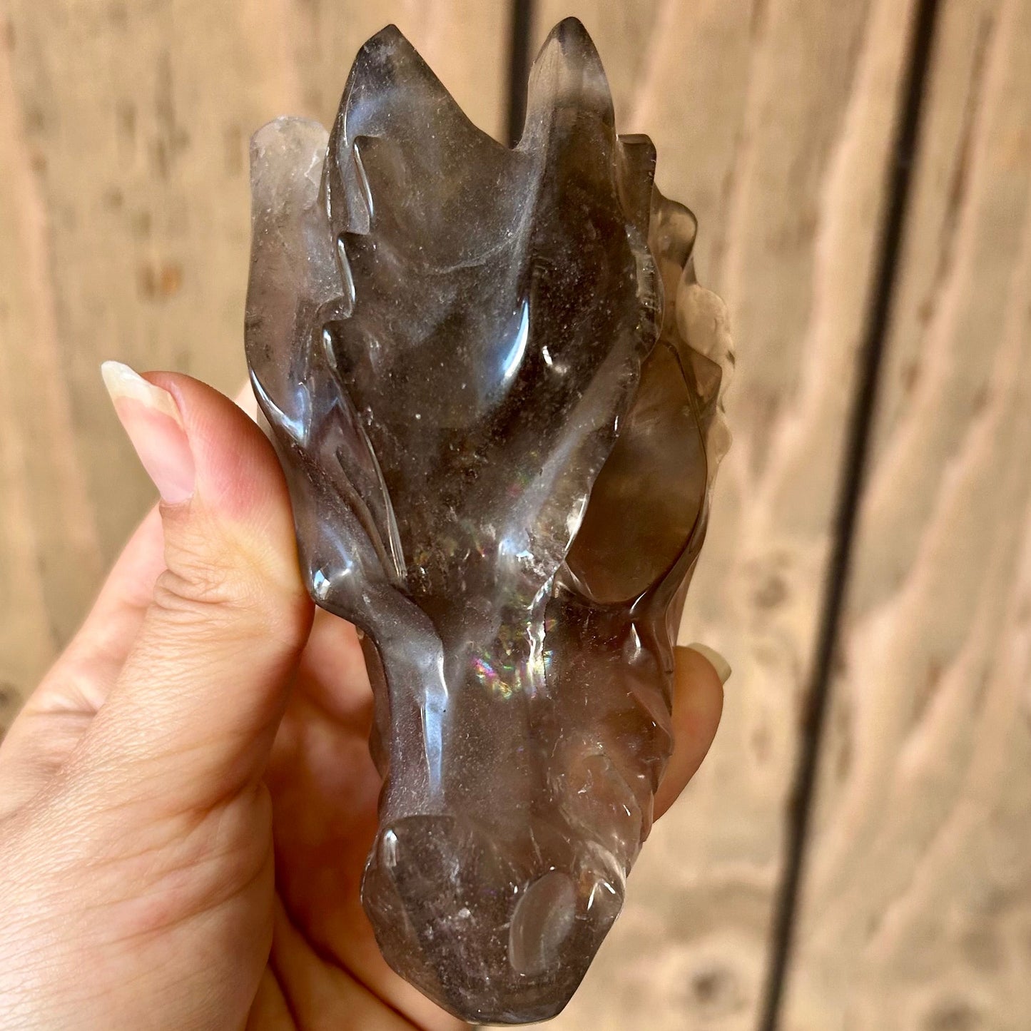 Hand holding a crystal animal figure against a wooden background