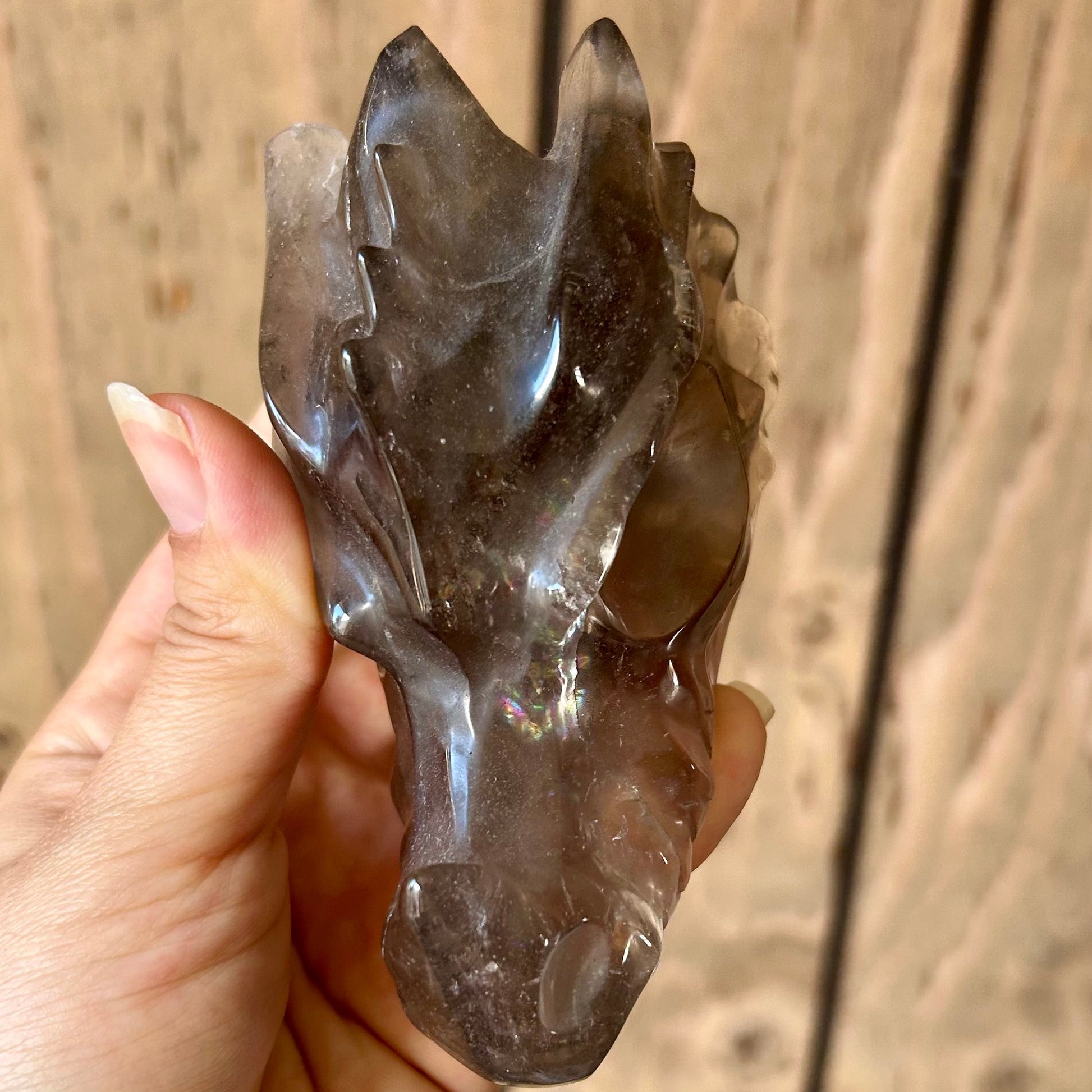 Hand holding a crystal animal figure against a wooden background