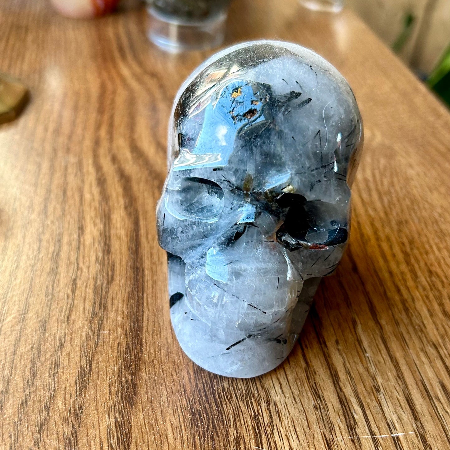 Crystal skull on a wooden surface with other crystals in the background
