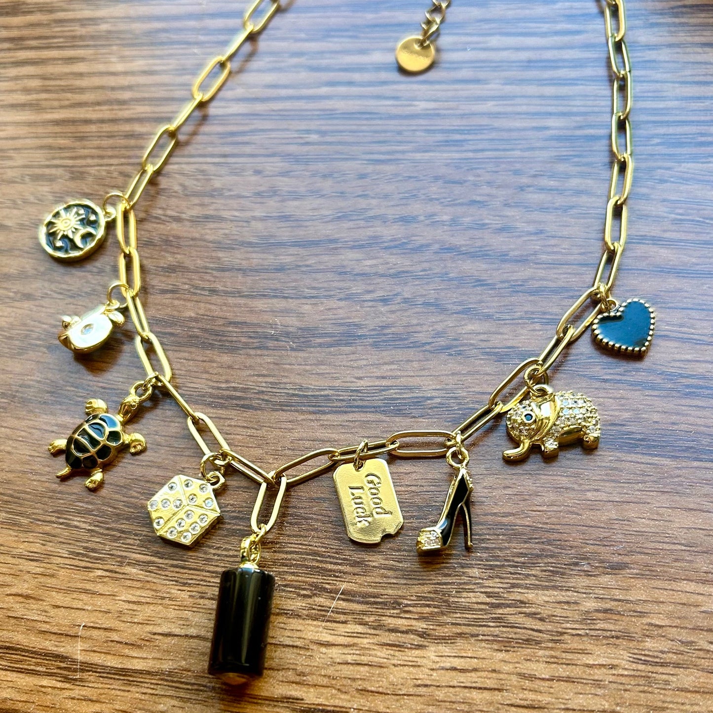 Gold necklace with various charms on a wooden surface