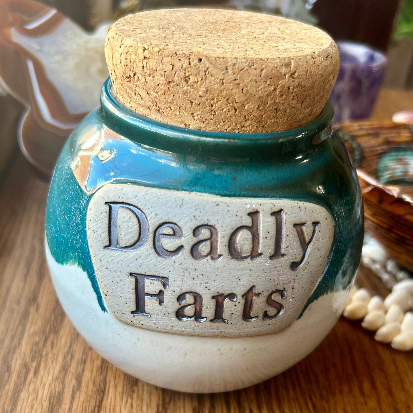 Small jar with cork lid labeled 'Deadly Farts' on a wooden surface.