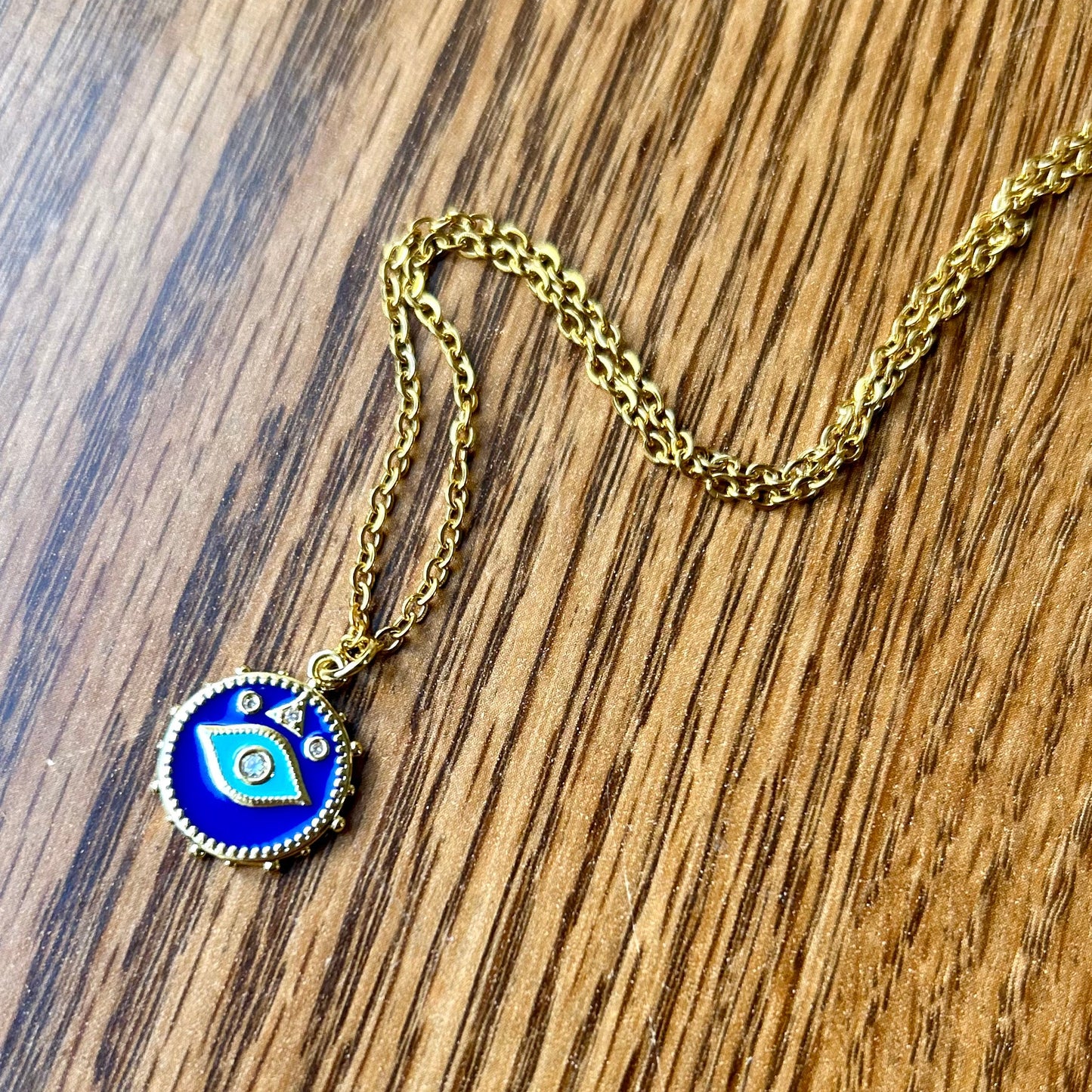 Gold necklace with a blue pendant on a wooden surface