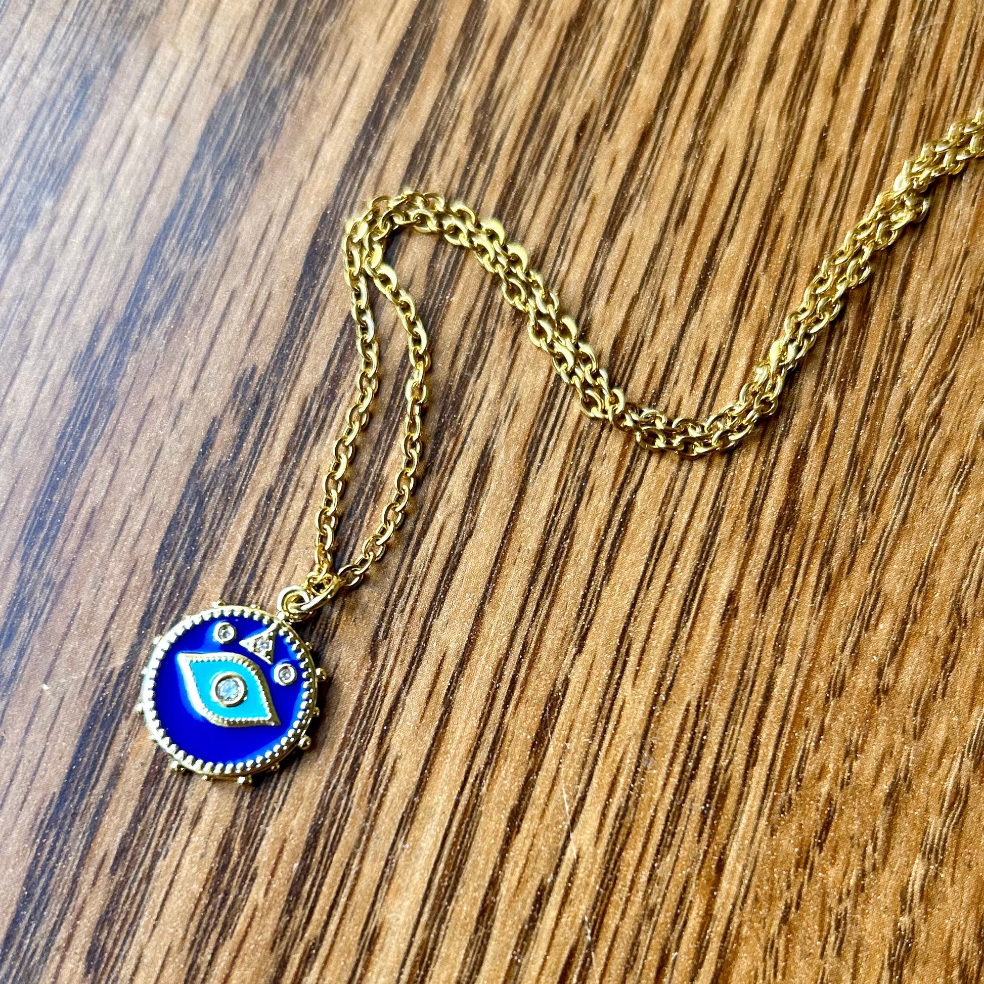 Gold necklace with a blue pendant on a wooden surface
