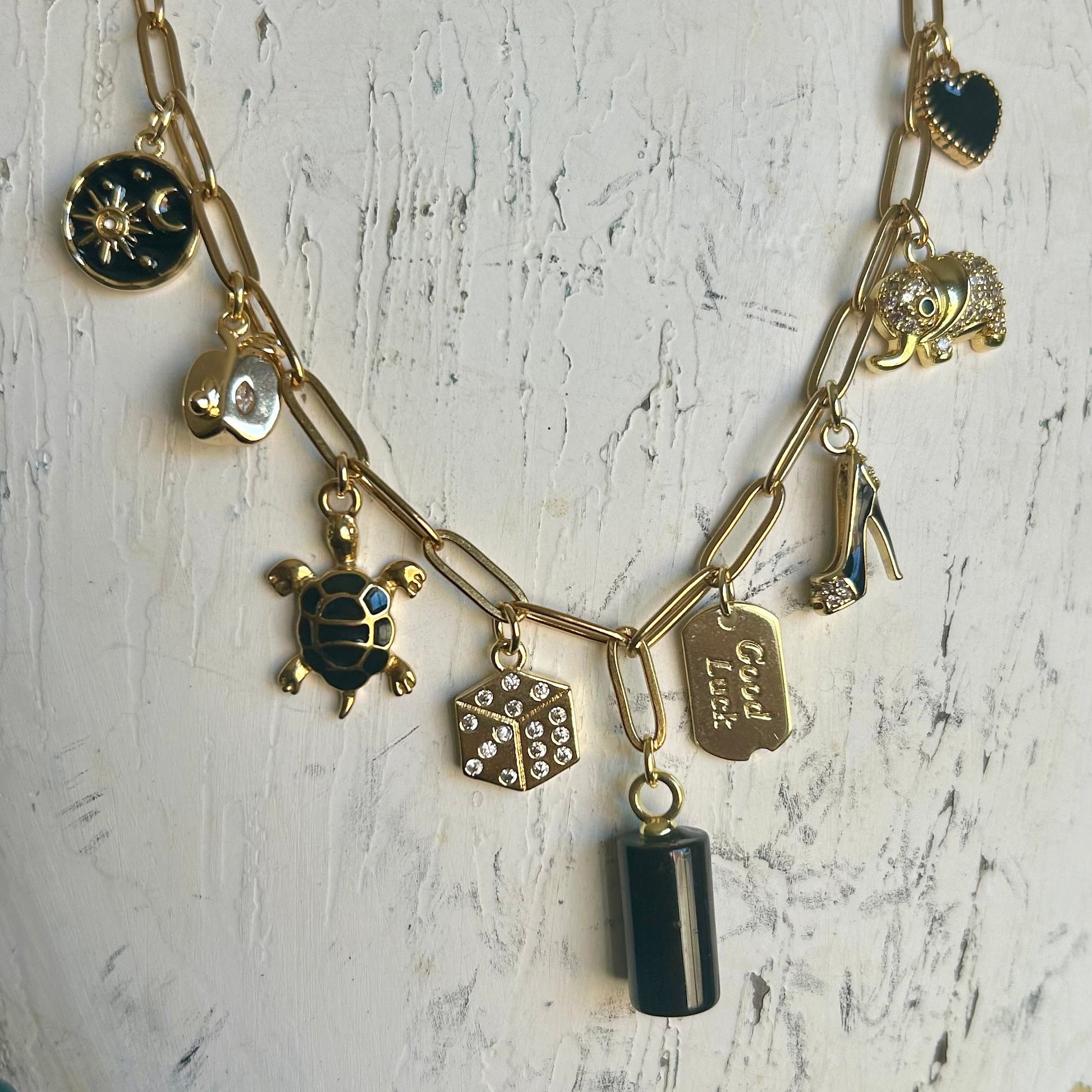 Necklace with various charms on a mannequin head against a white background