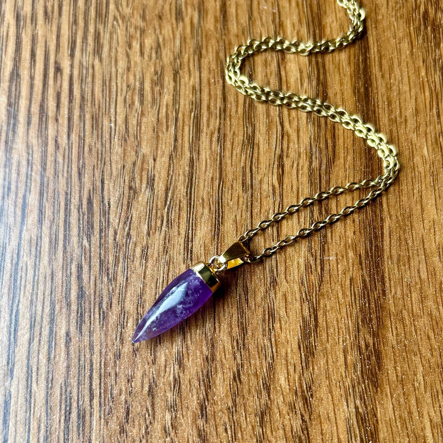 Necklace with a purple pendant on a wooden surface