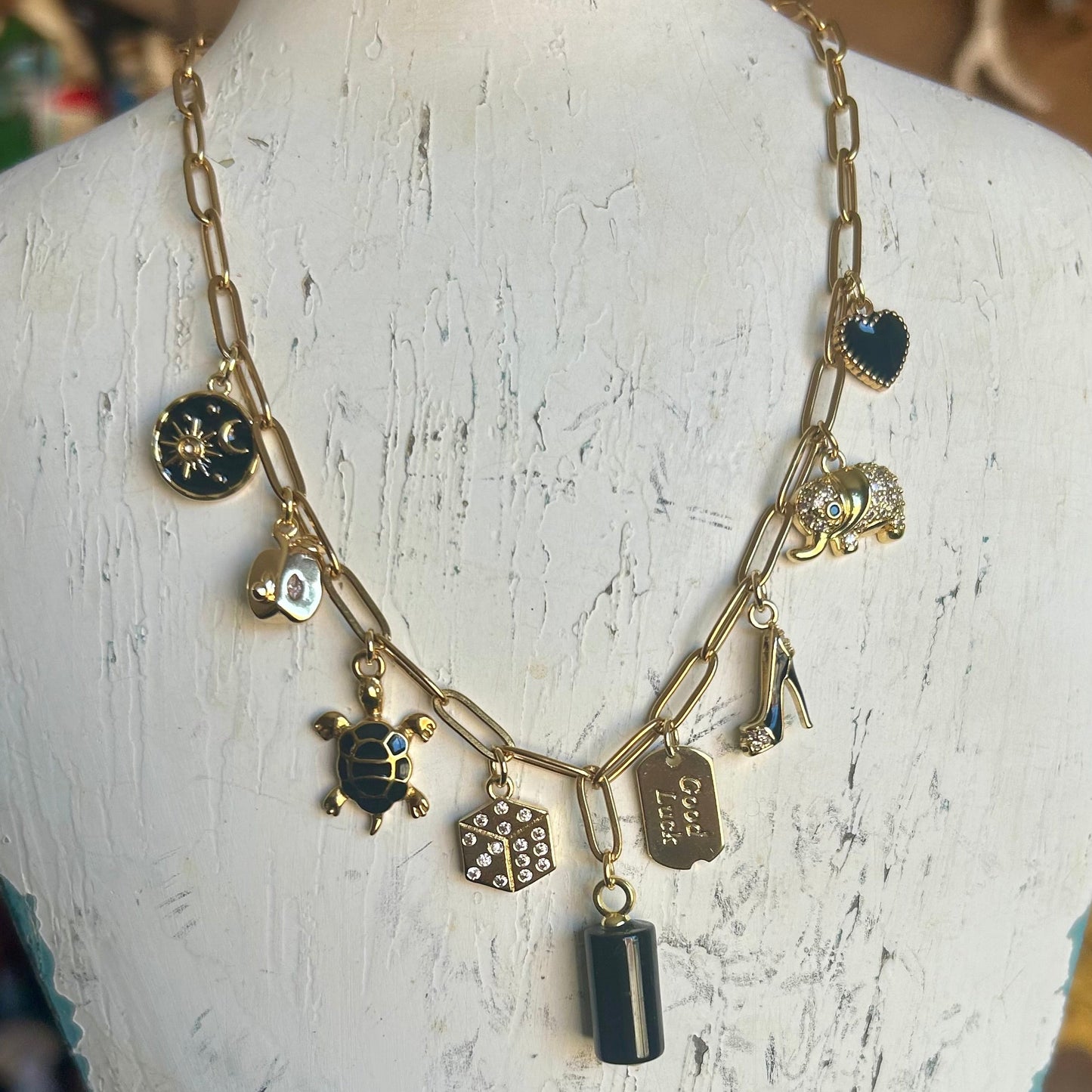 Necklace with various charms on a white mannequin bust.